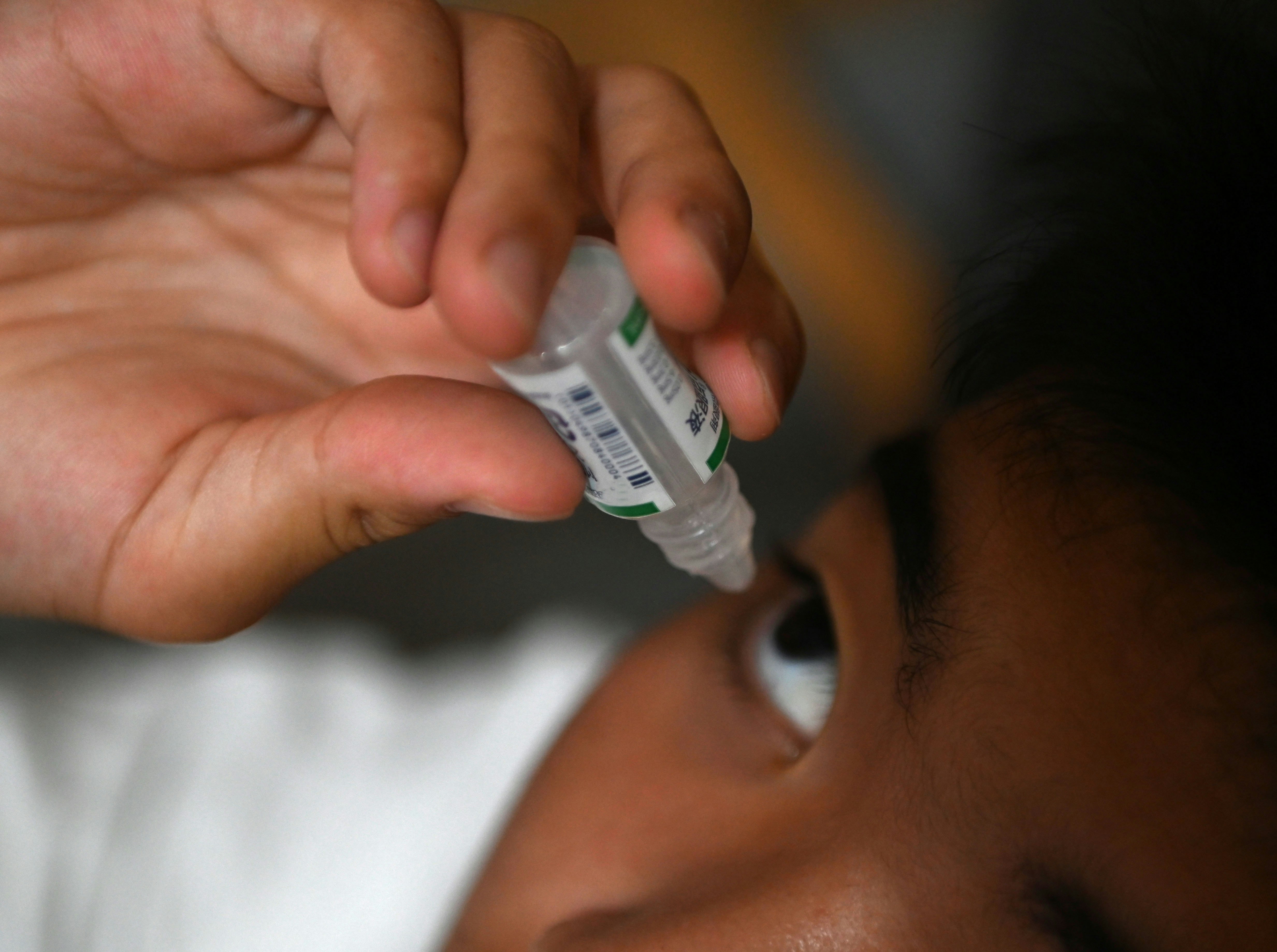 注射器で目薬を点眼する手と目元