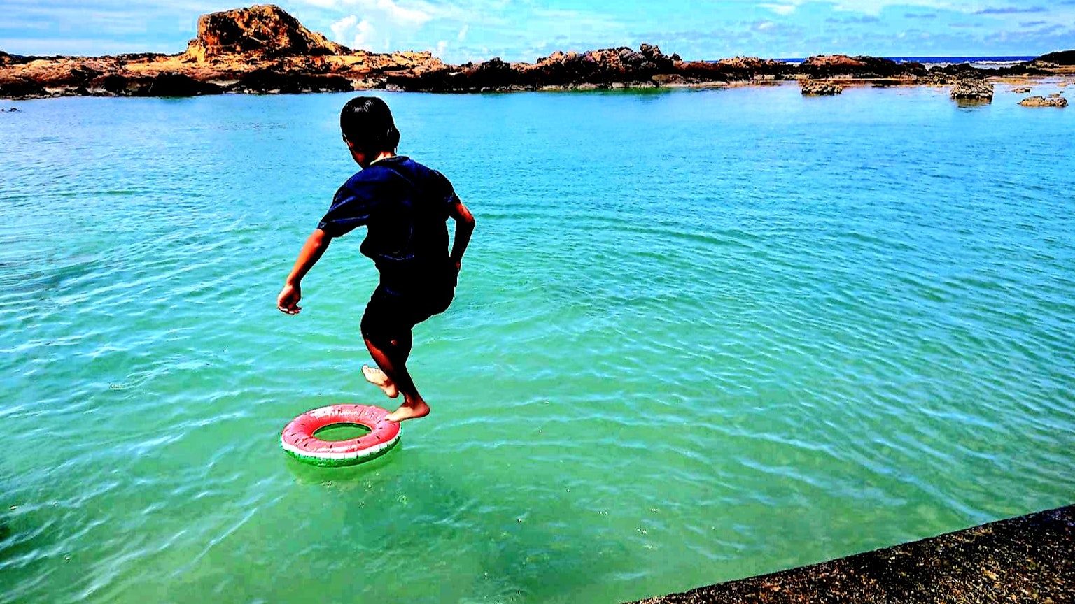 Child standing on a float in the blue sea