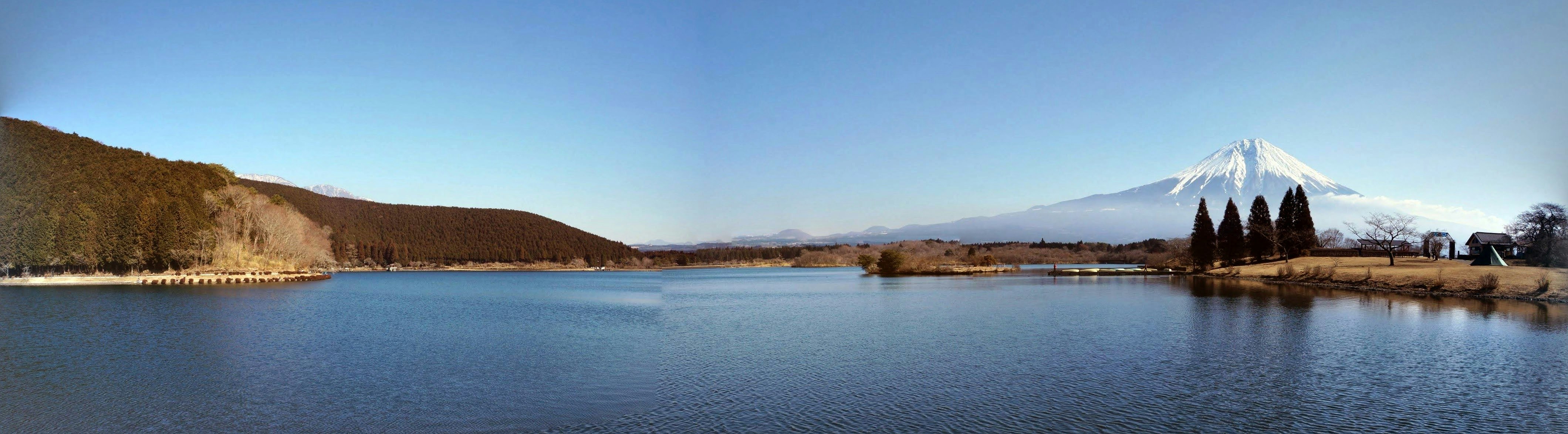 A calm lakeside water surface with distant mountain range in winter