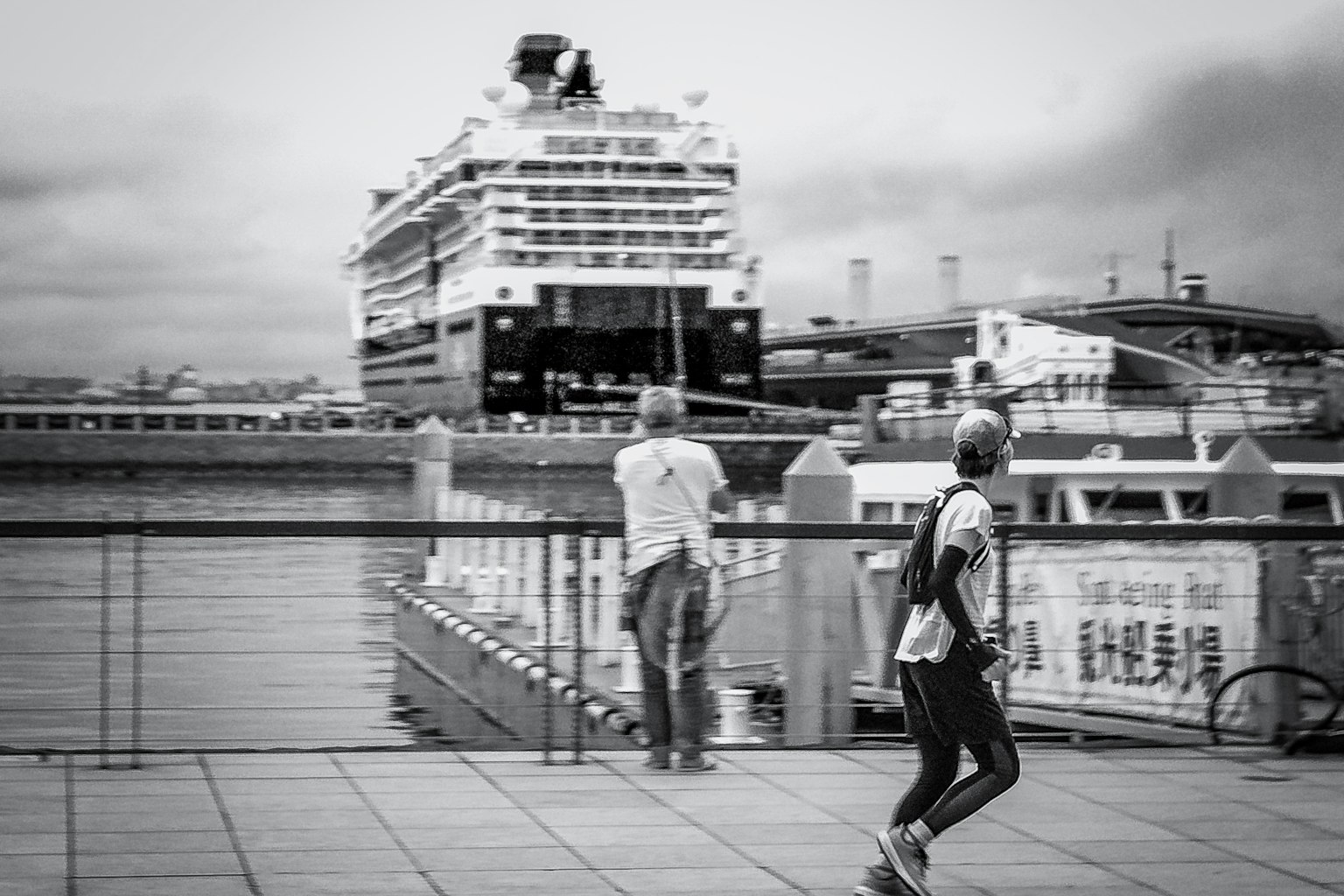 Personas caminando en una escena en blanco y negro con un crucero al fondo