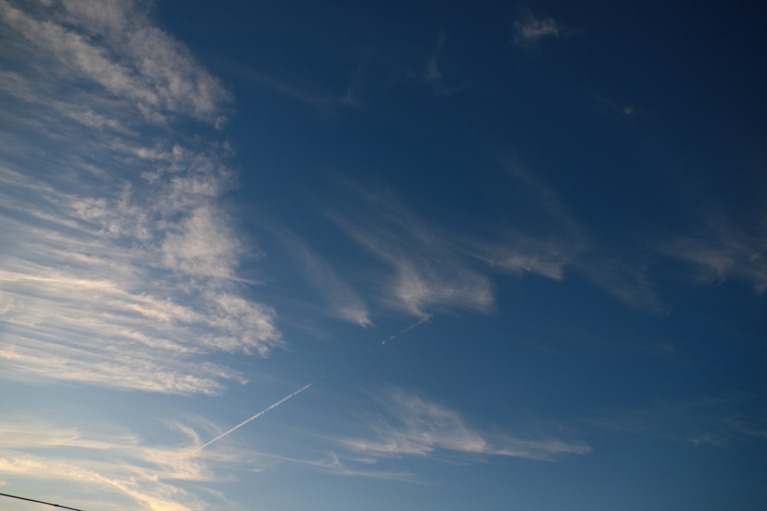Wolkenmuster in einem blauen Himmel mit einem Kondensstreifen