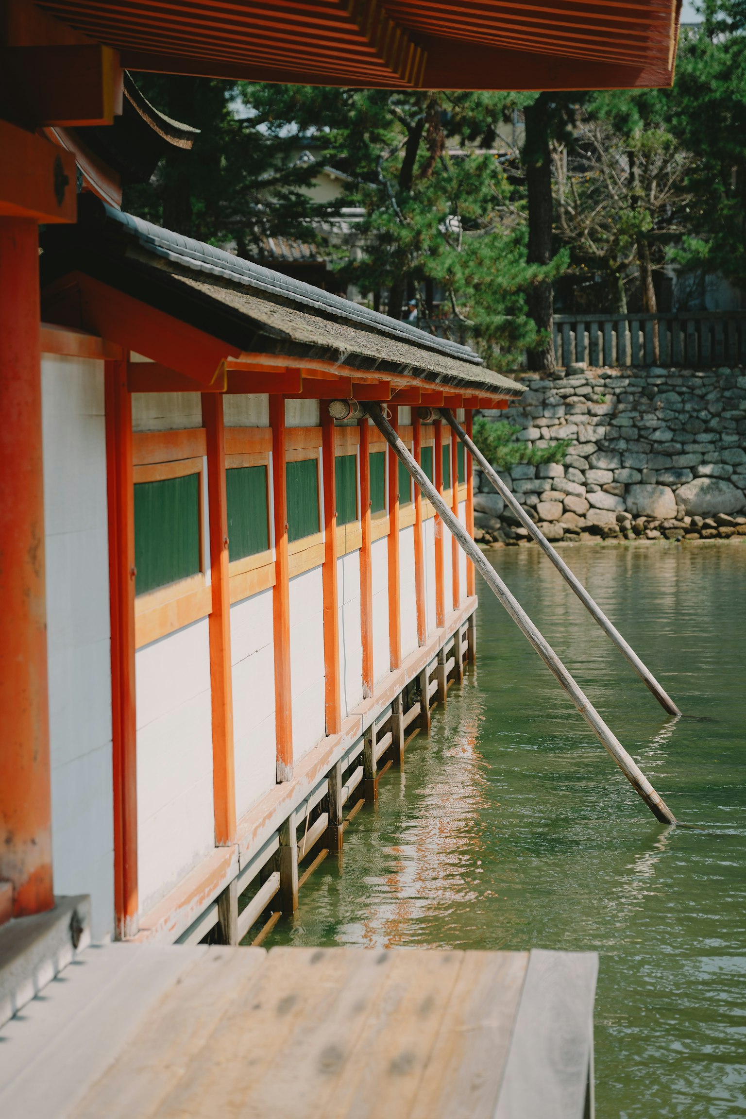 Partie d'une structure japonaise traditionnelle au bord de l'eau avec des piliers rouges et des fenêtres vertes
