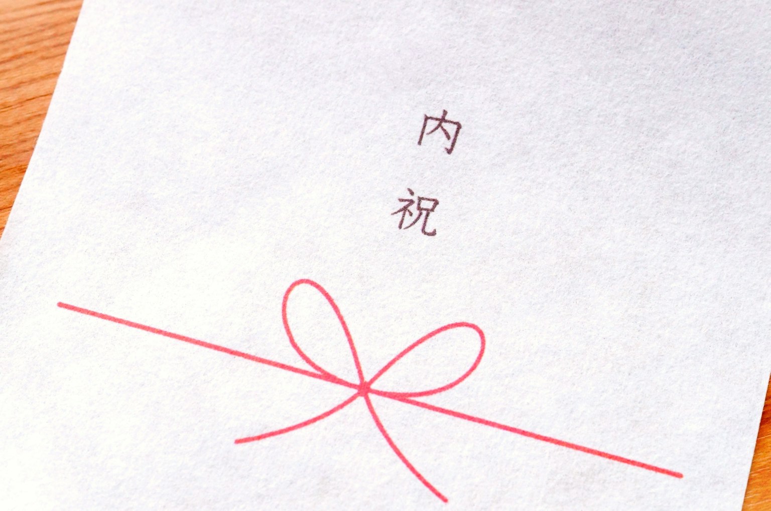 Un foglio con un fiocco rosso e il testo 内祝