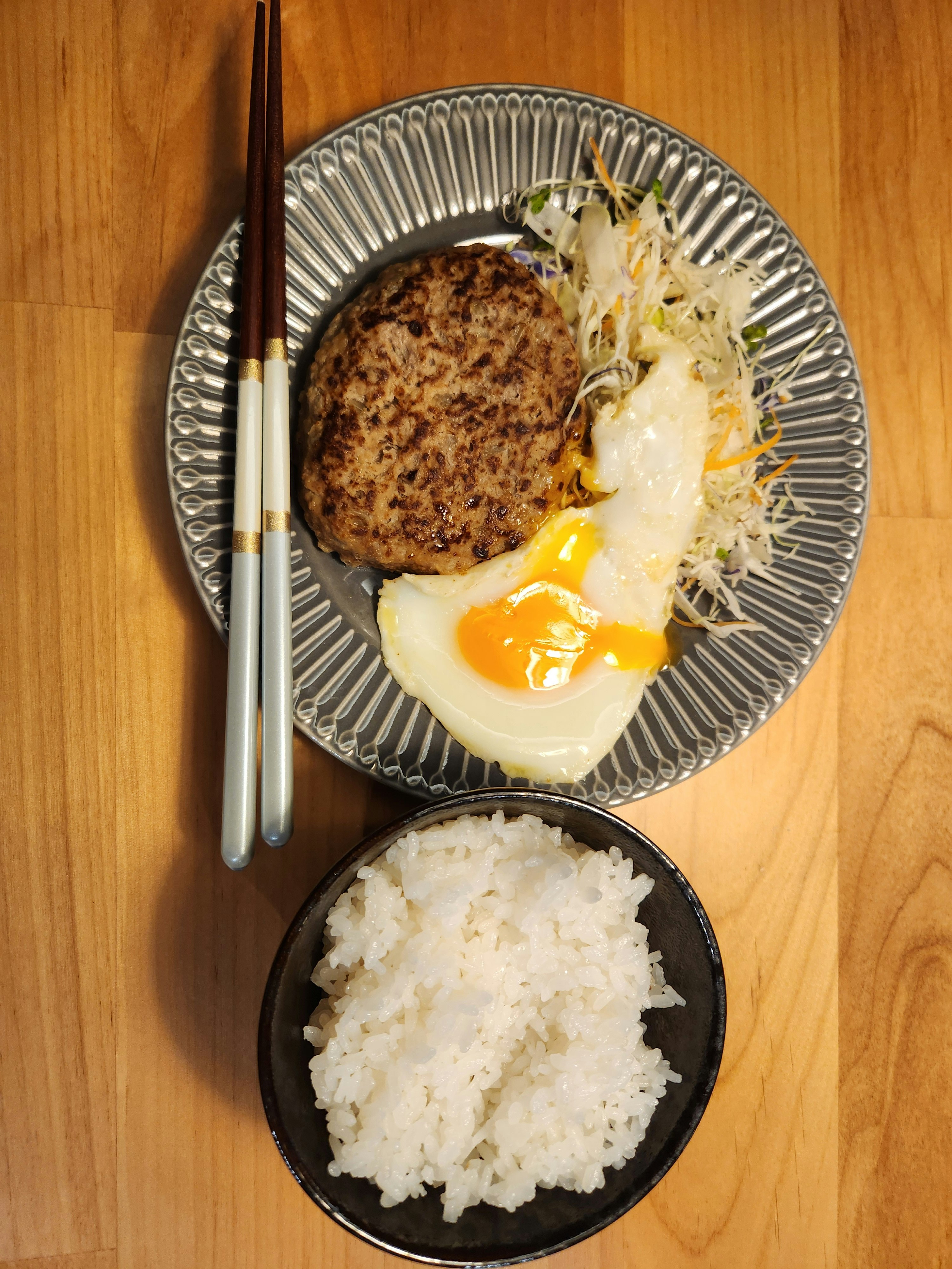 木桌上的煎蛋与汉堡排配白米饭