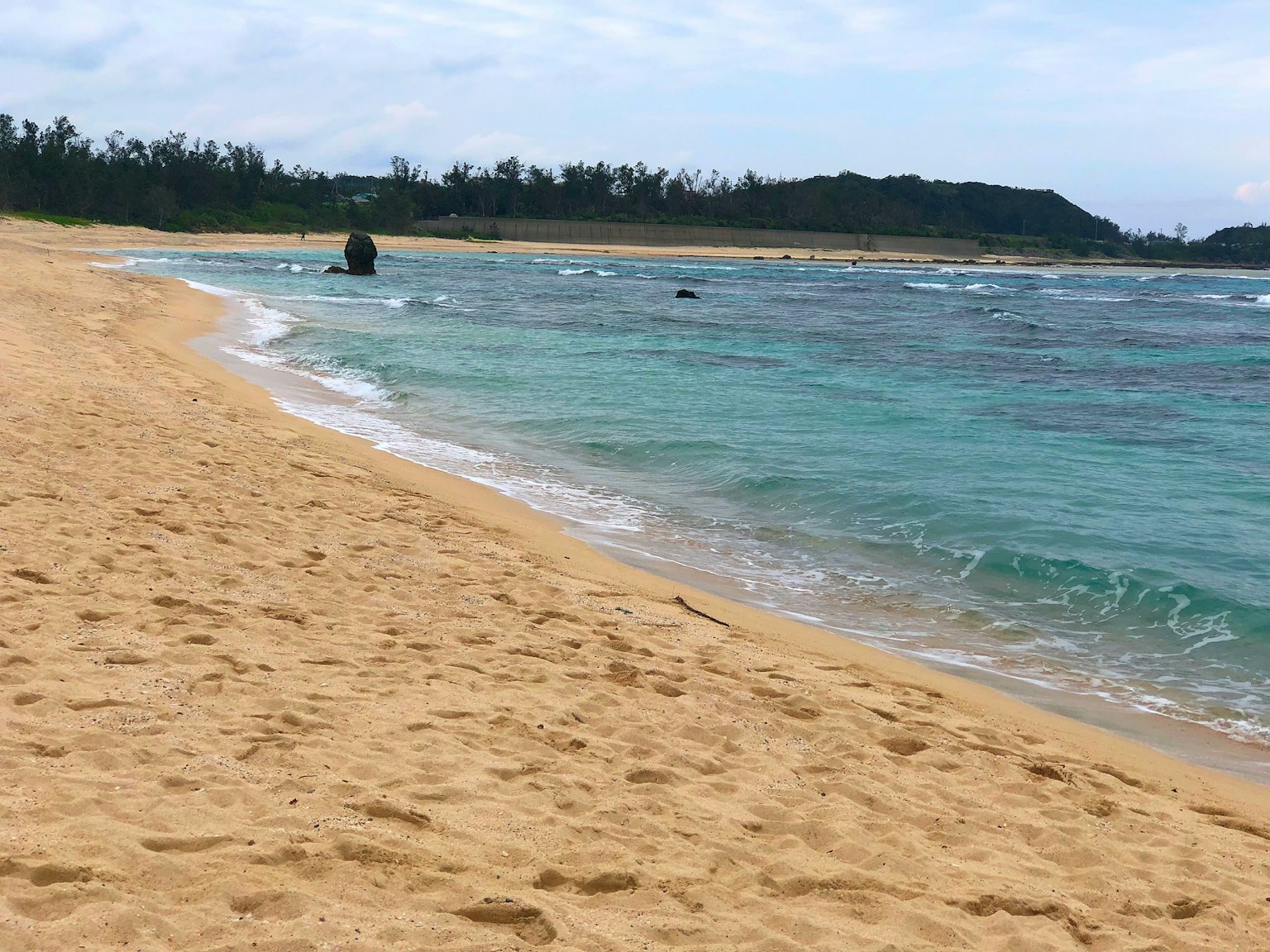 ชายหาดที่มีทิวทัศน์สวยงามพร้อมน้ำสีฟ้าและชายหาดทราย