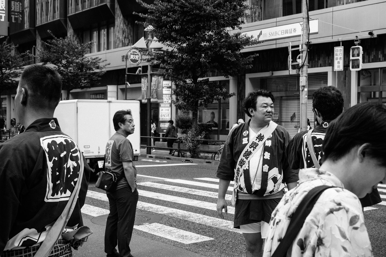 黒白の街中で伝統的な衣装を着た人々が交差点に立っている