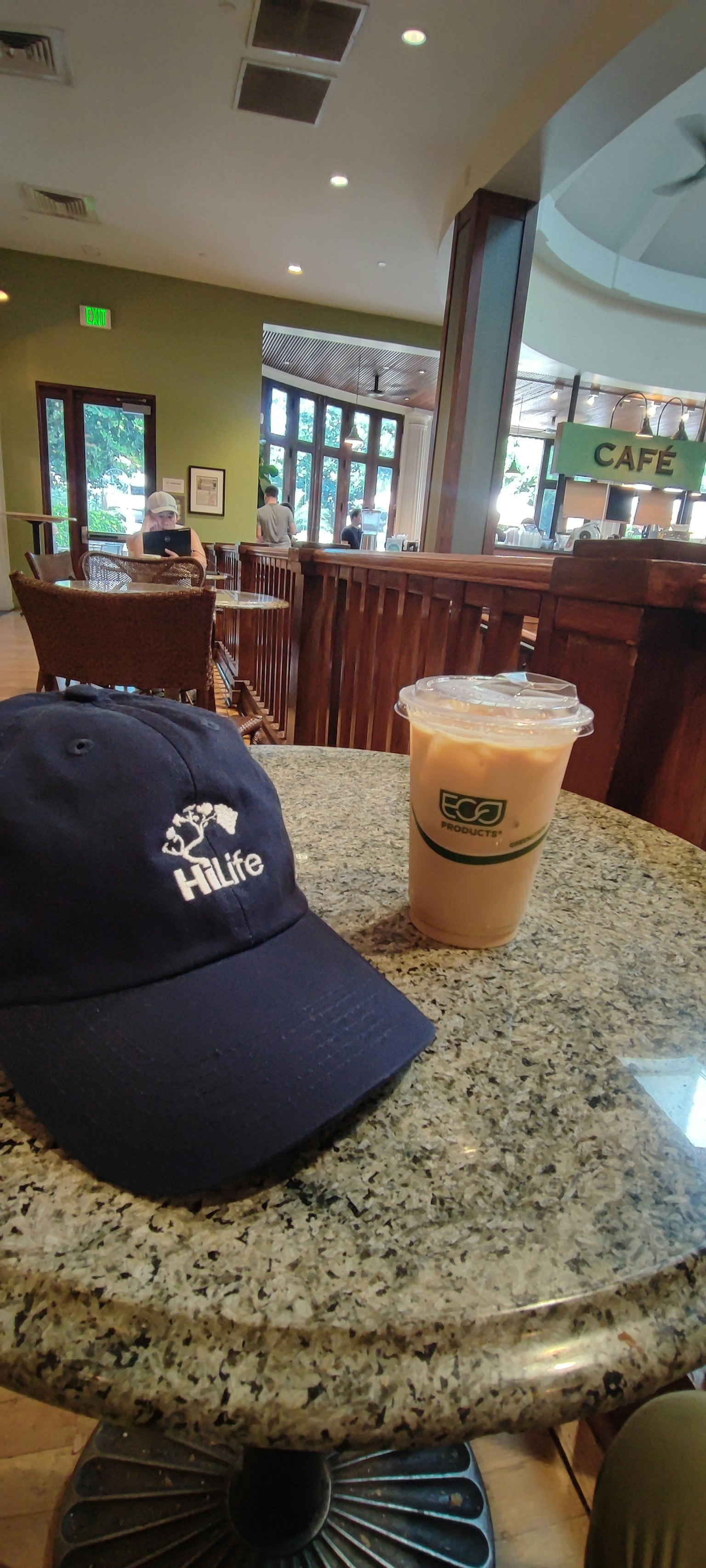 หมวกกับแก้วกาแฟเย็นบนโต๊ะ