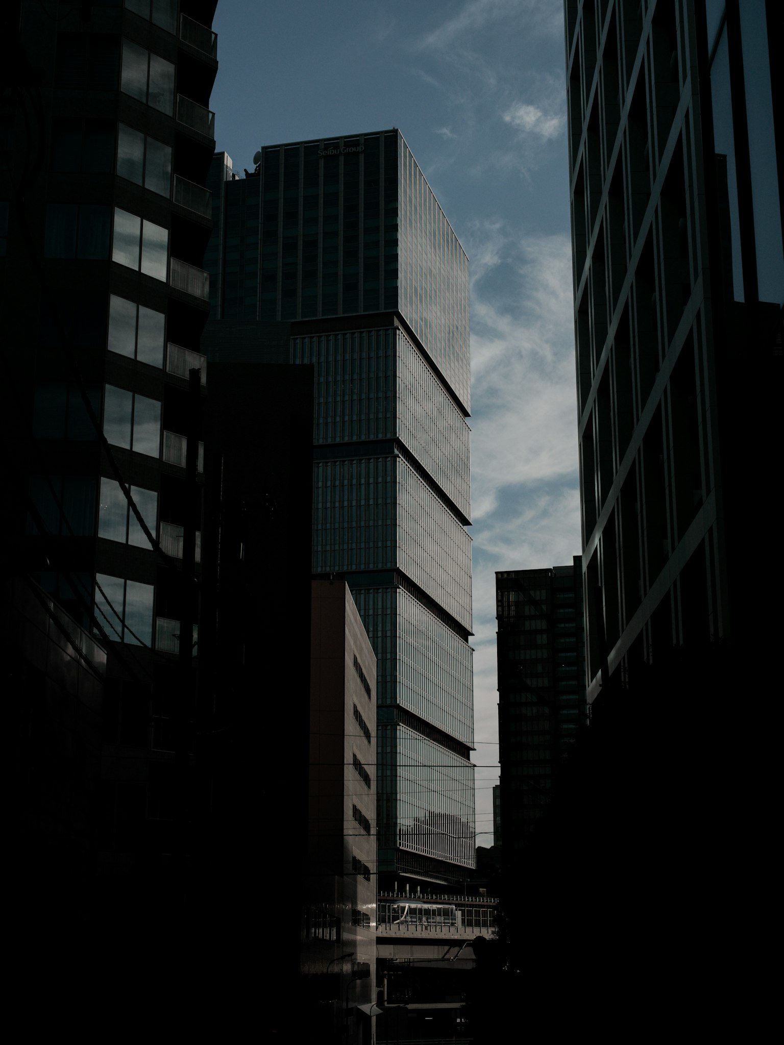 Silhouette d'un bâtiment moderne entouré de gratte-ciels ciel diurne avec des nuages