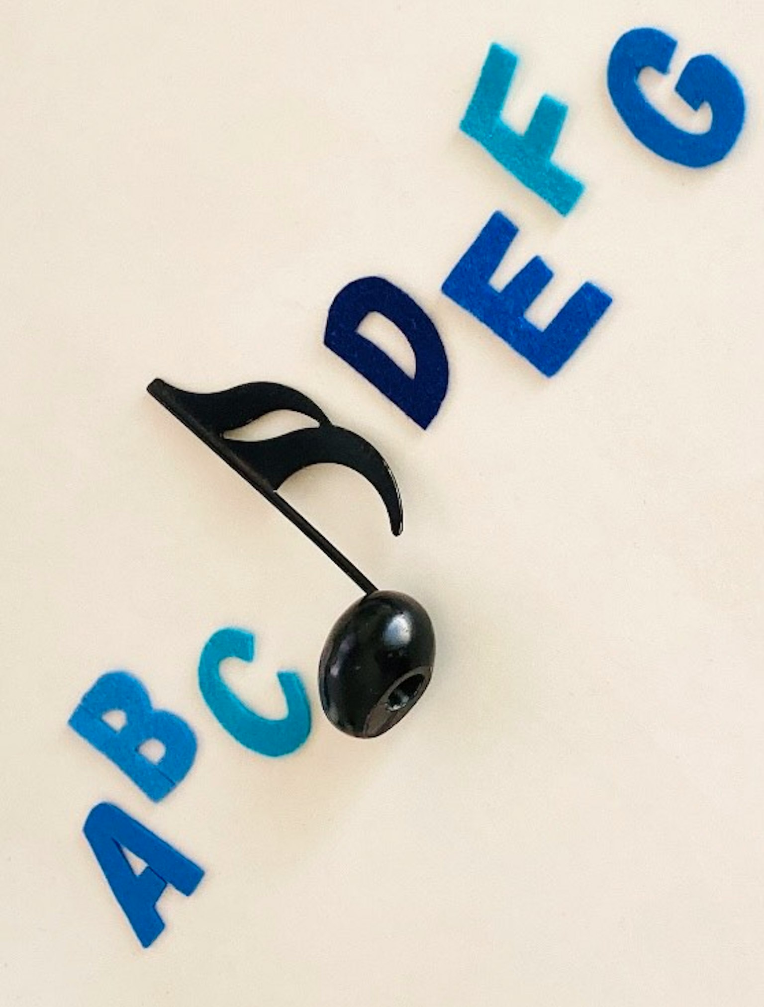 Nota musical negra rodeada de letras del alfabeto coloridas A B C D E F G