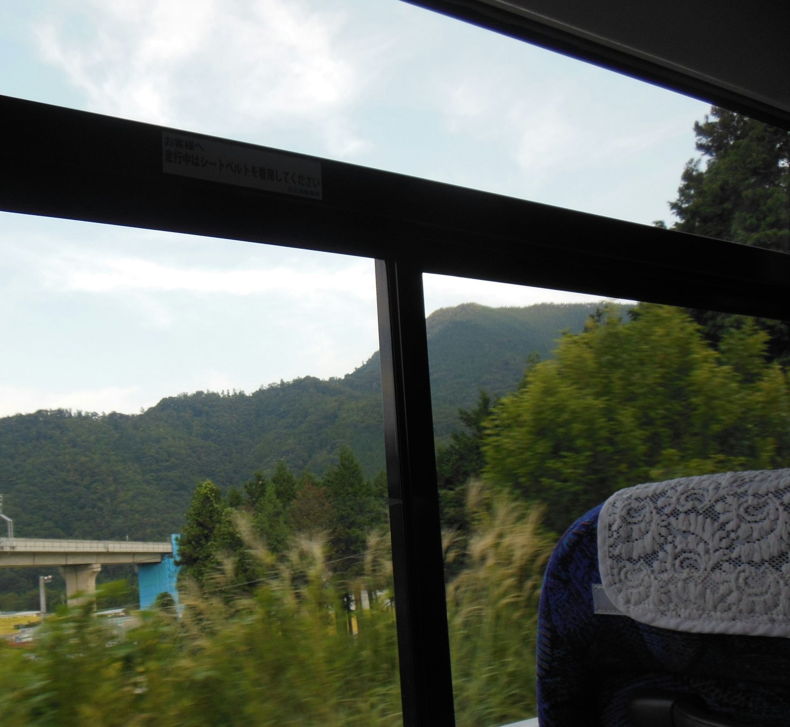 Scenic view of mountains and greenery through a bus window
