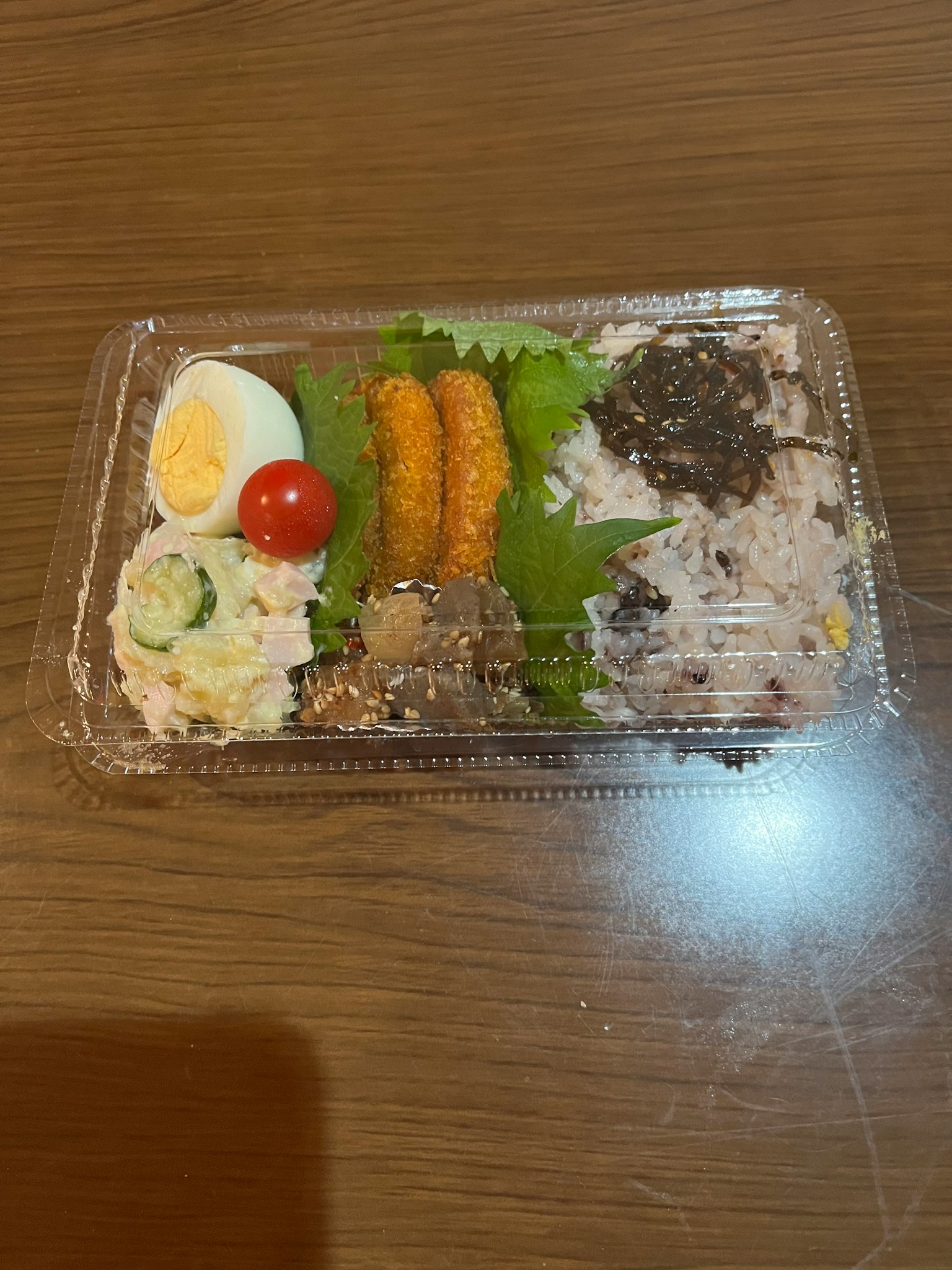 Caja bento con huevo duro tomate cherry ensalada croquetas y algas