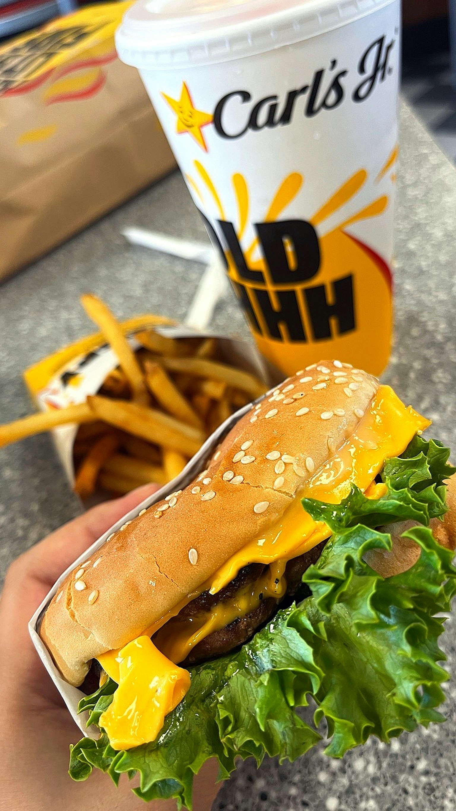 Burger Carl's Jr avec laitue et fromage accompagné de frites et d'une boisson