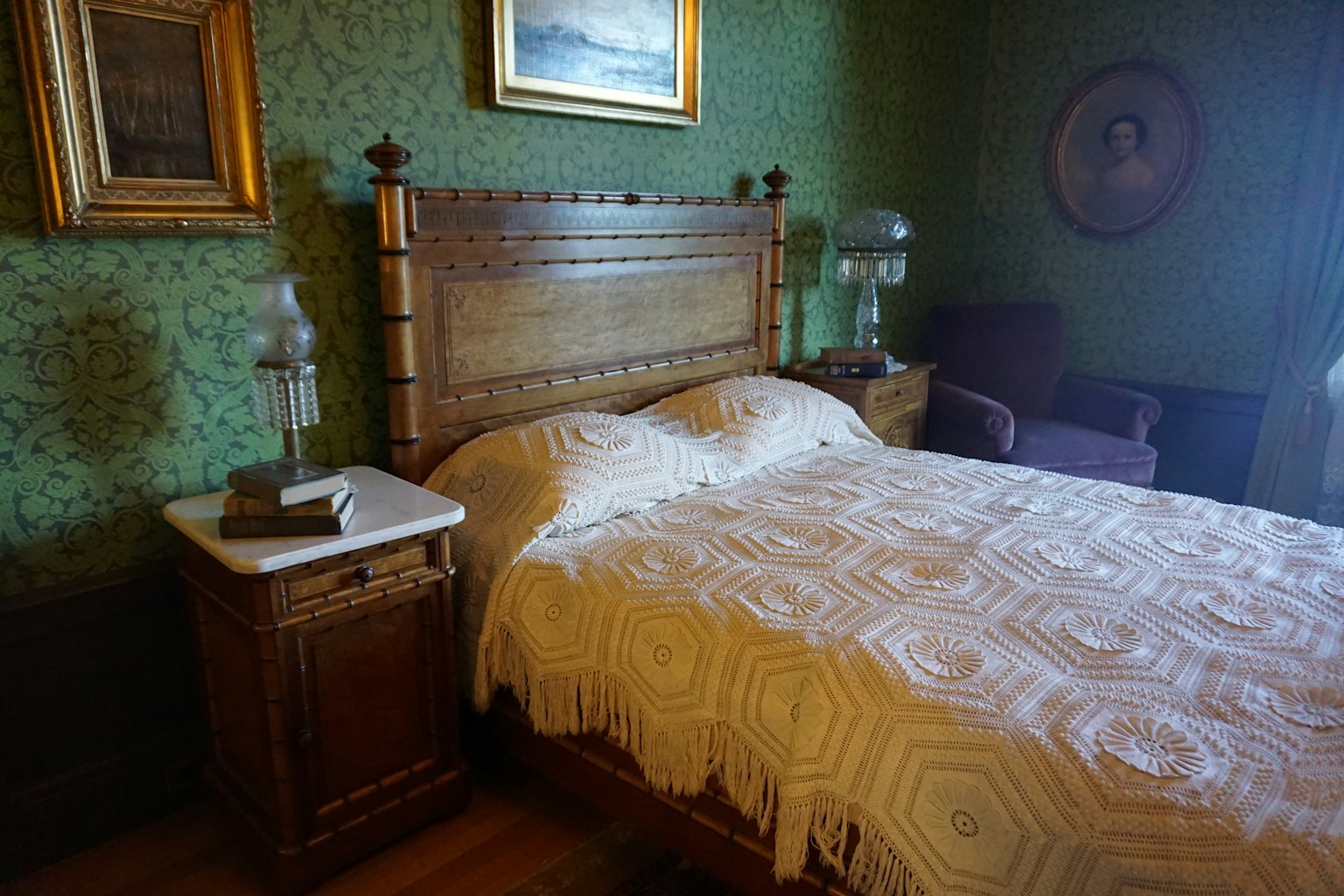 Tempat tidur kayu dengan selimut bermotif di ruang dinding hijau