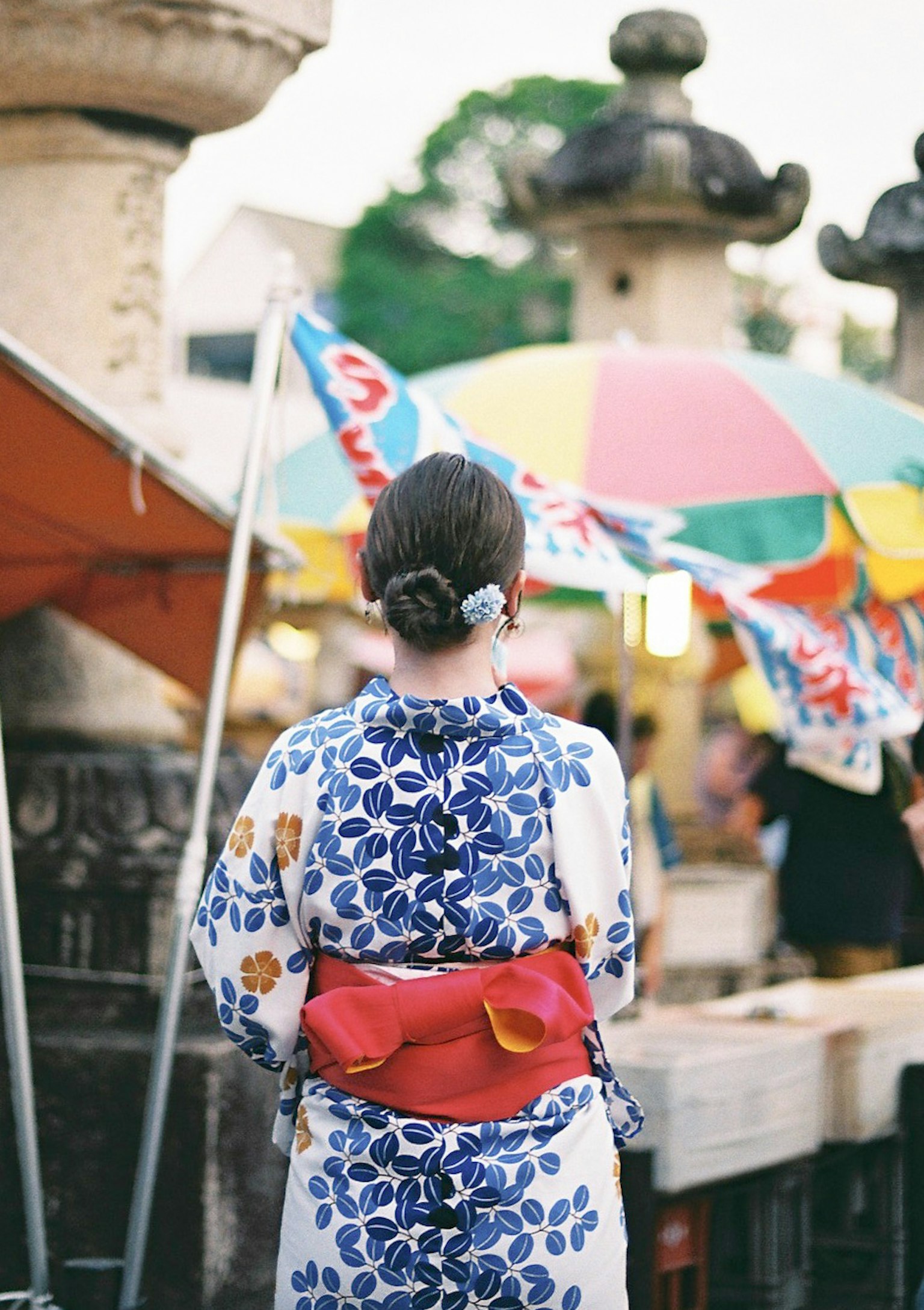 一位穿著和服的女性背對鏡頭站在五彩伞下