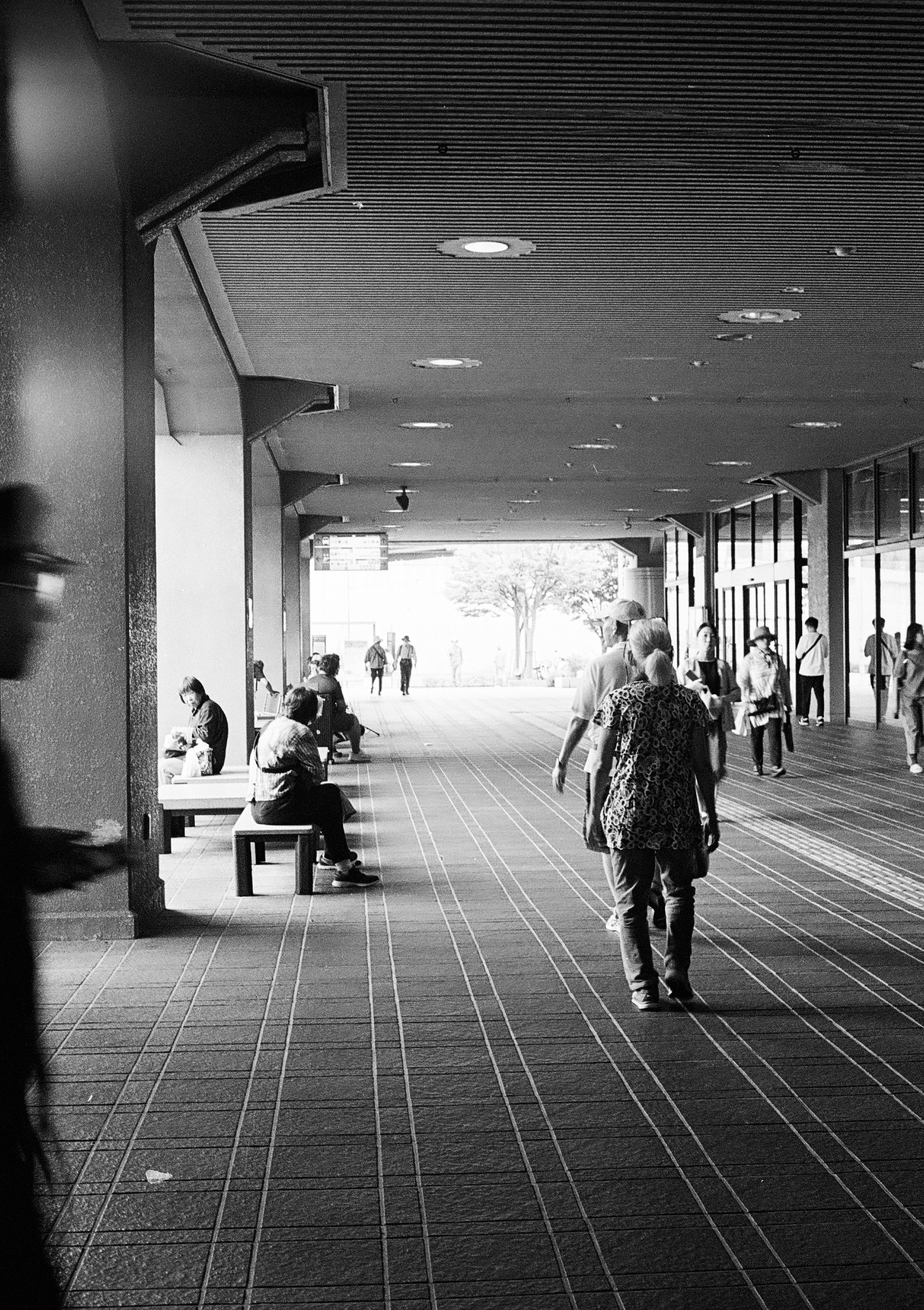 アーケード状の回廊を歩く人々とベンチのある通路