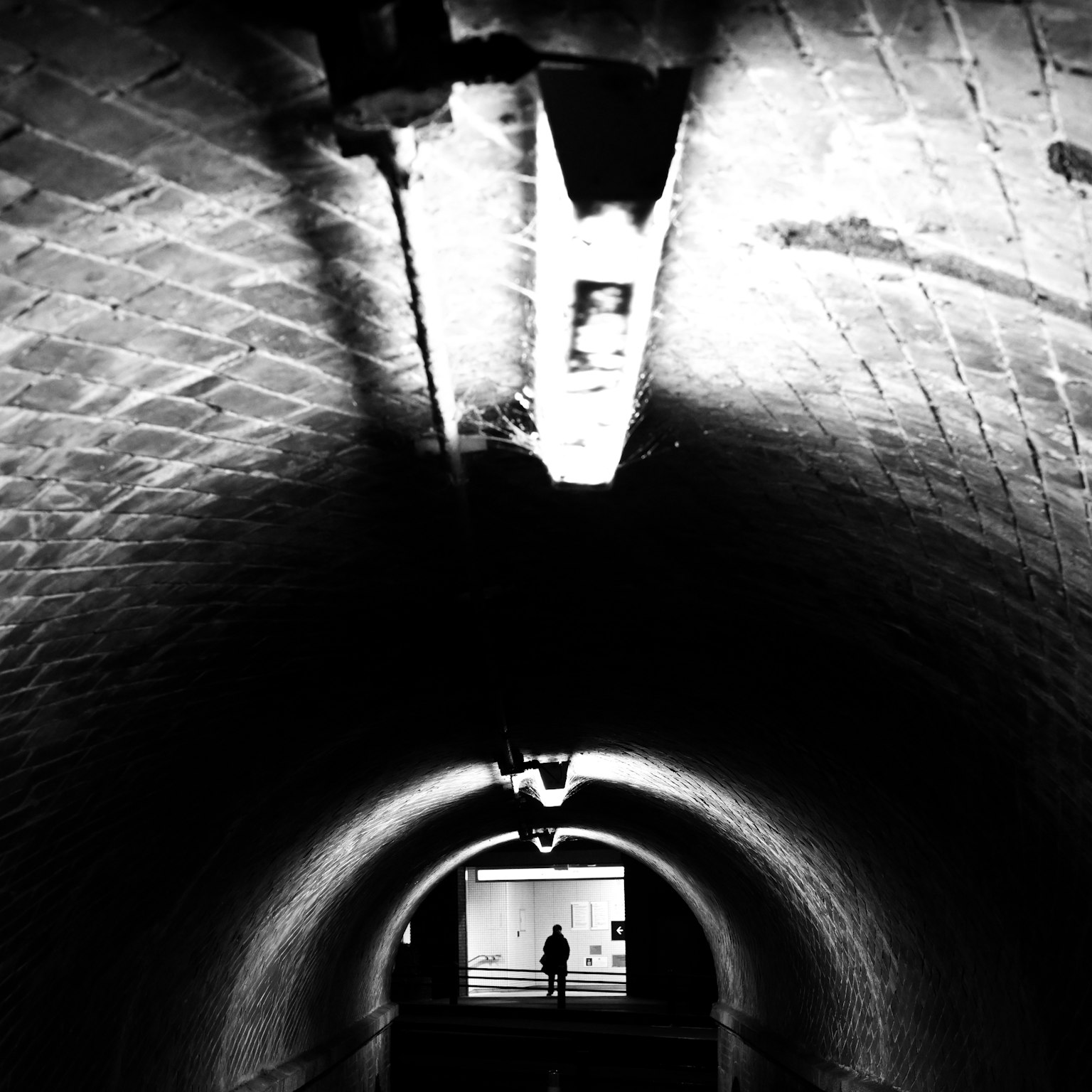 Una silueta de una persona de pie al final de un túnel oscuro con una salida brillante