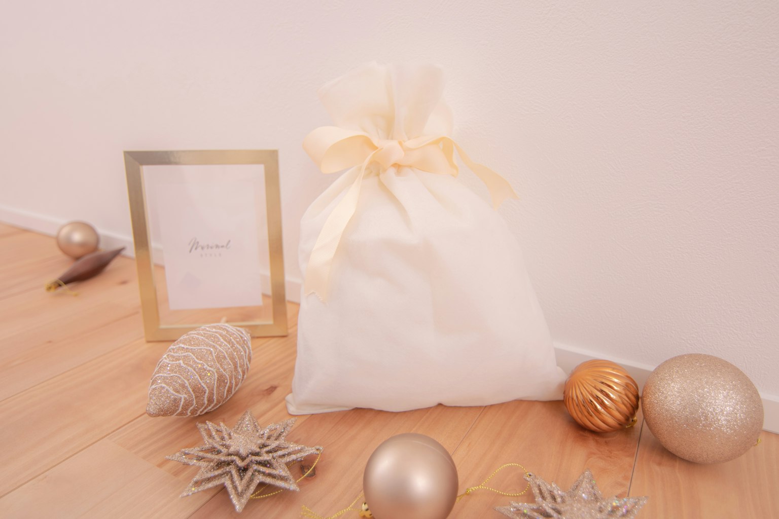 A white fabric bag tied with a ribbon surrounded by gold and silver ornaments