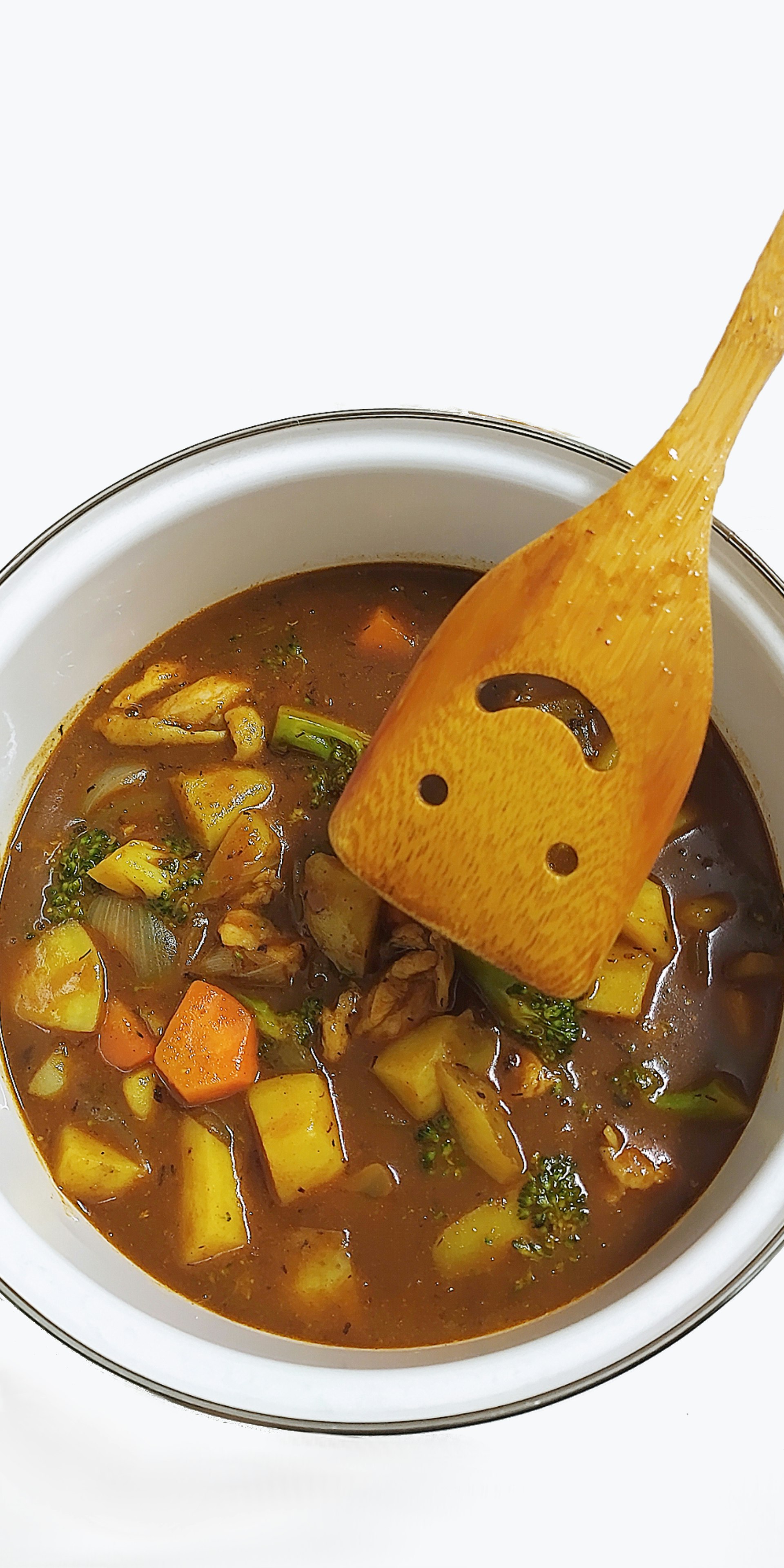 カレー鍋に木べらで具材をすくう手作りカレーの一皿