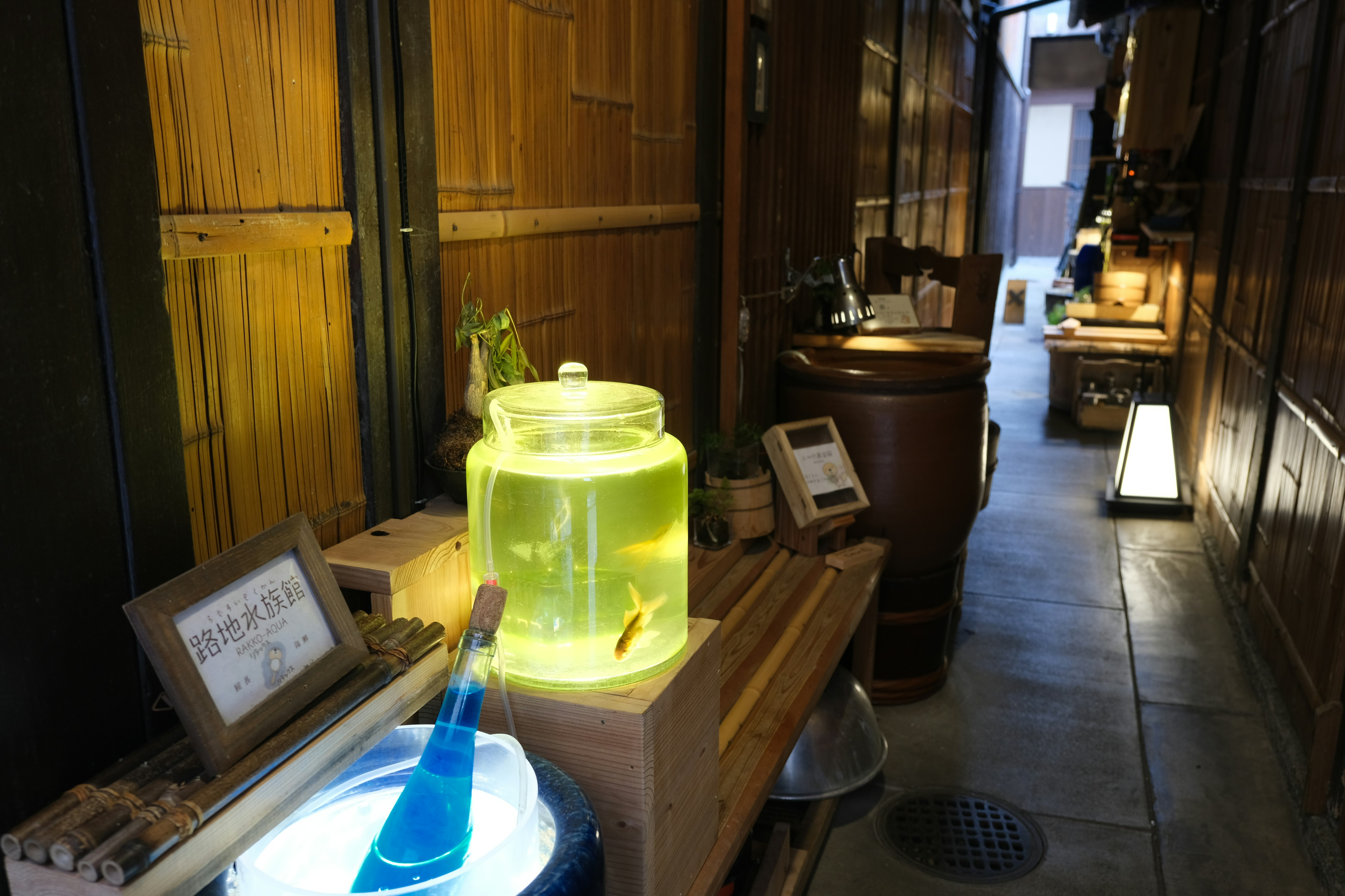 路地の木造の小さな店先に並ぶ行灯と置物