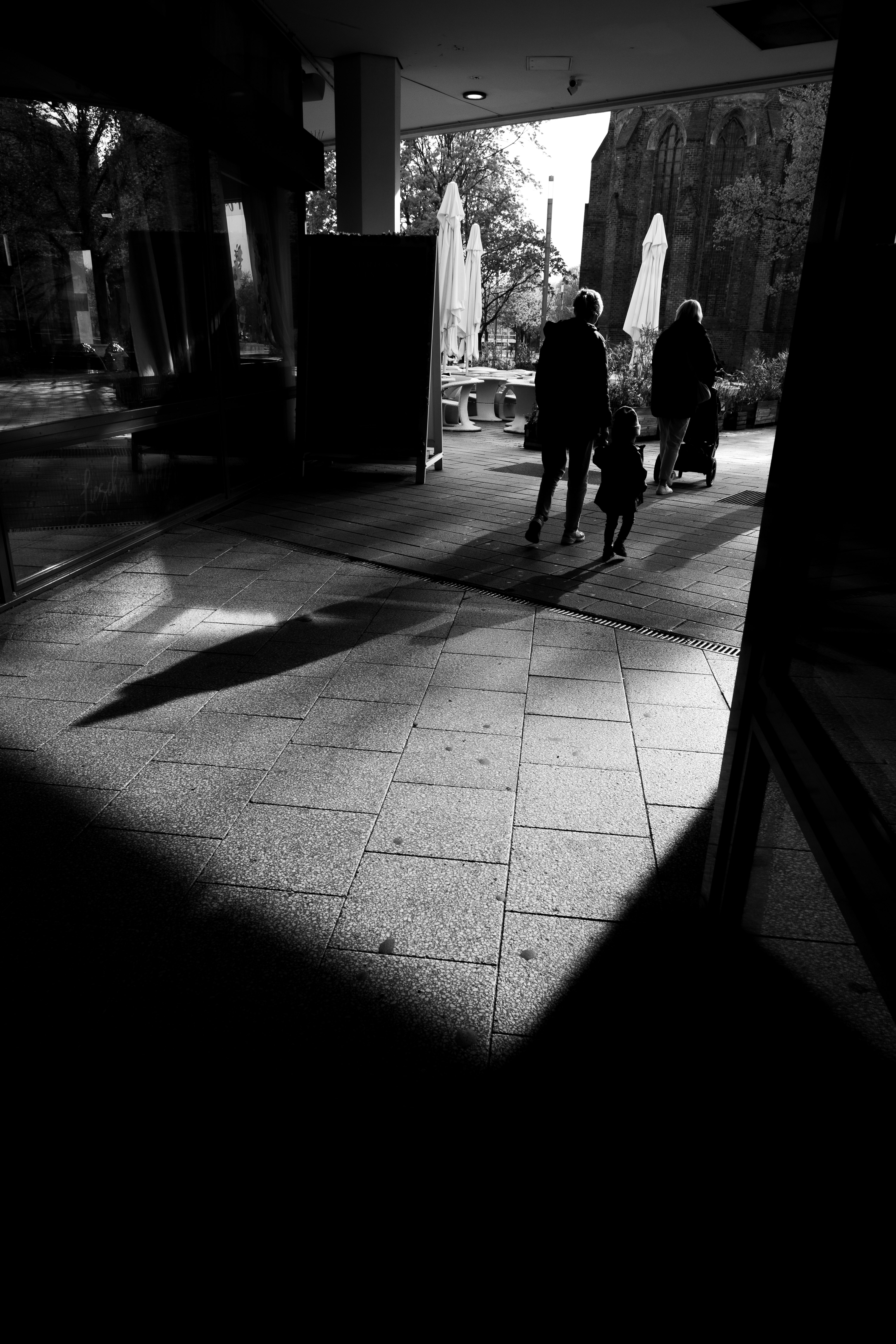 persone in silhouette che camminano in un corridoio di pietra ad arco