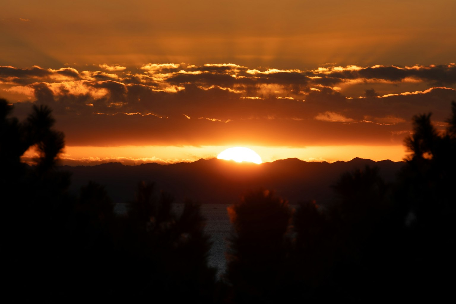 Bellissimo paesaggio del tramonto che sorge tra le montagne con varie sfumature di arancione e giallo