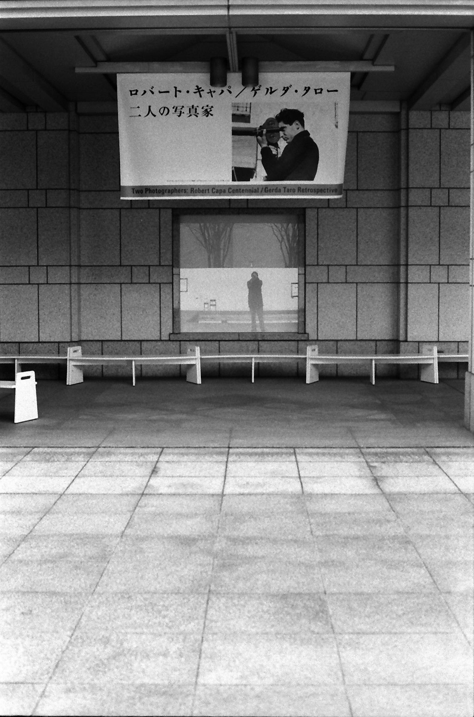 Photo en noir et blanc d'une salle d'attente de gare vide avec l'ombre d'une personne