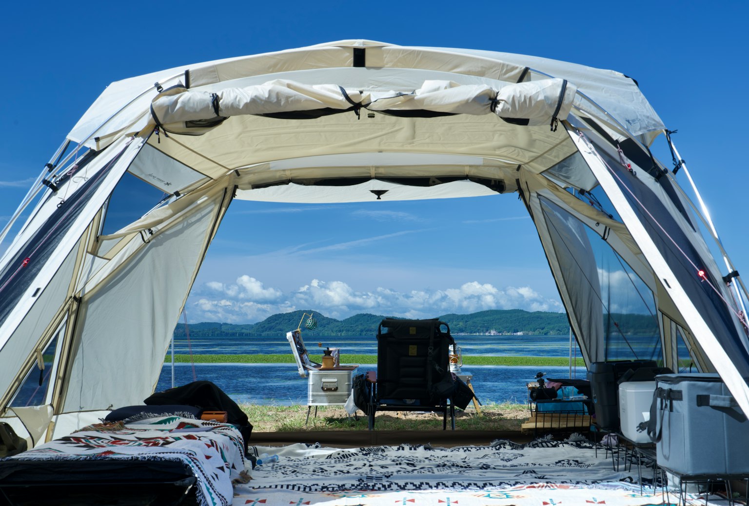 青空の下に広がるテントの内部からの眺め 海と山々が見える