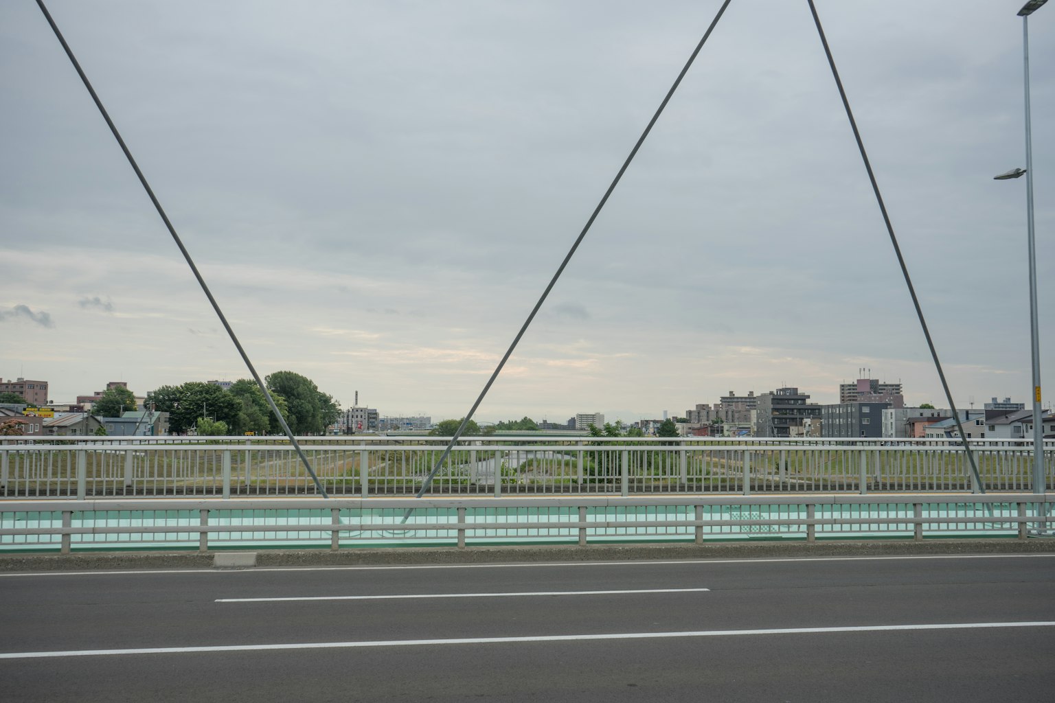 Pont suspendu avec ciel gris et bâtiments visibles au loin