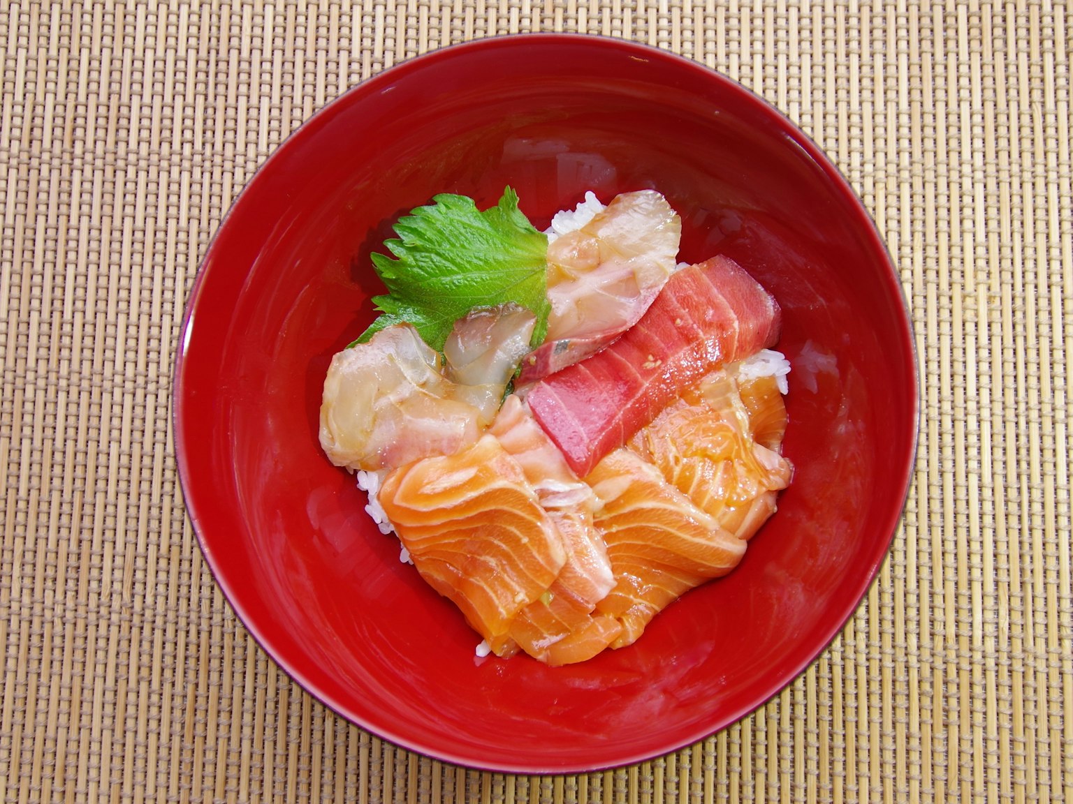 Ciotola di riso con sashimi di salmone e tonno in un piatto rosso