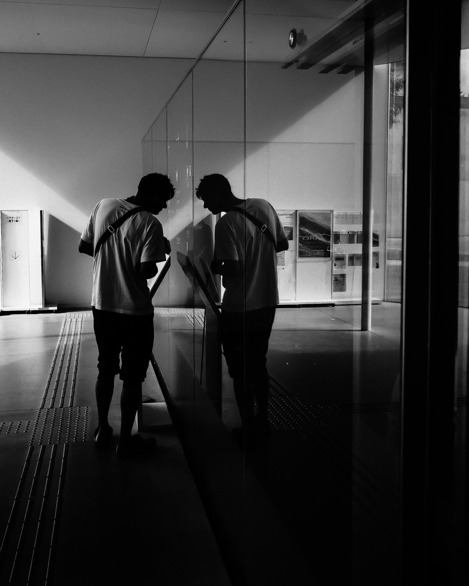 Two men observing something in front of a mirror in a black and white image