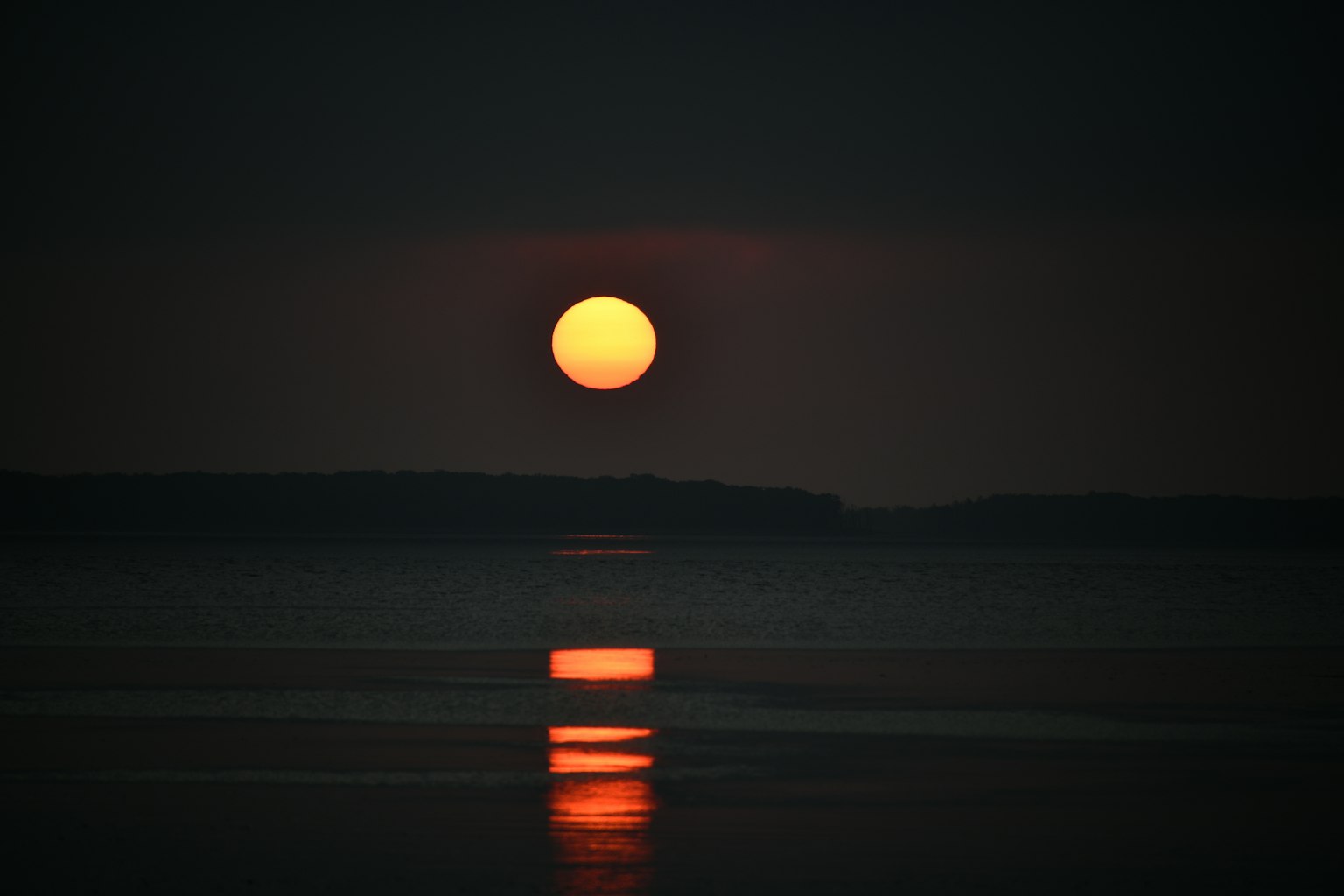Atardecer sobre agua oscura con reflejos