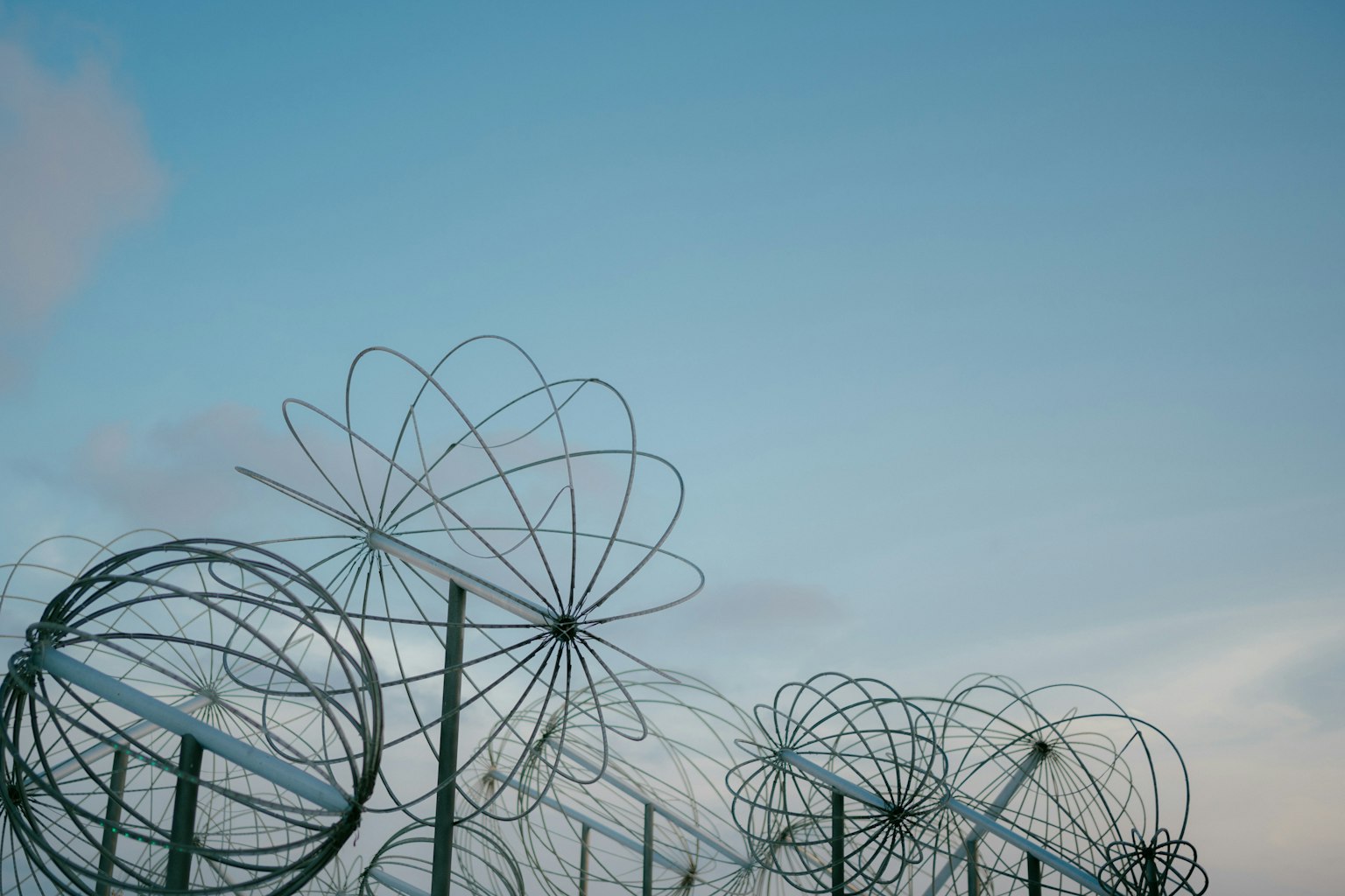 Esculturas metálicas alineadas bajo un cielo azul