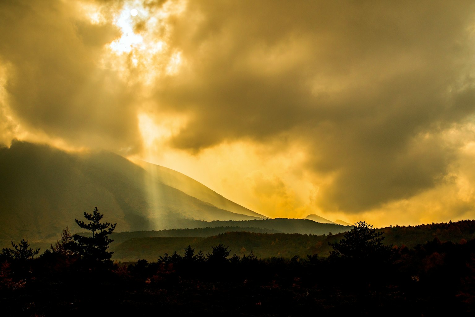 Landschaft mit Bergen und goldenem Licht, das durch Wolken bricht