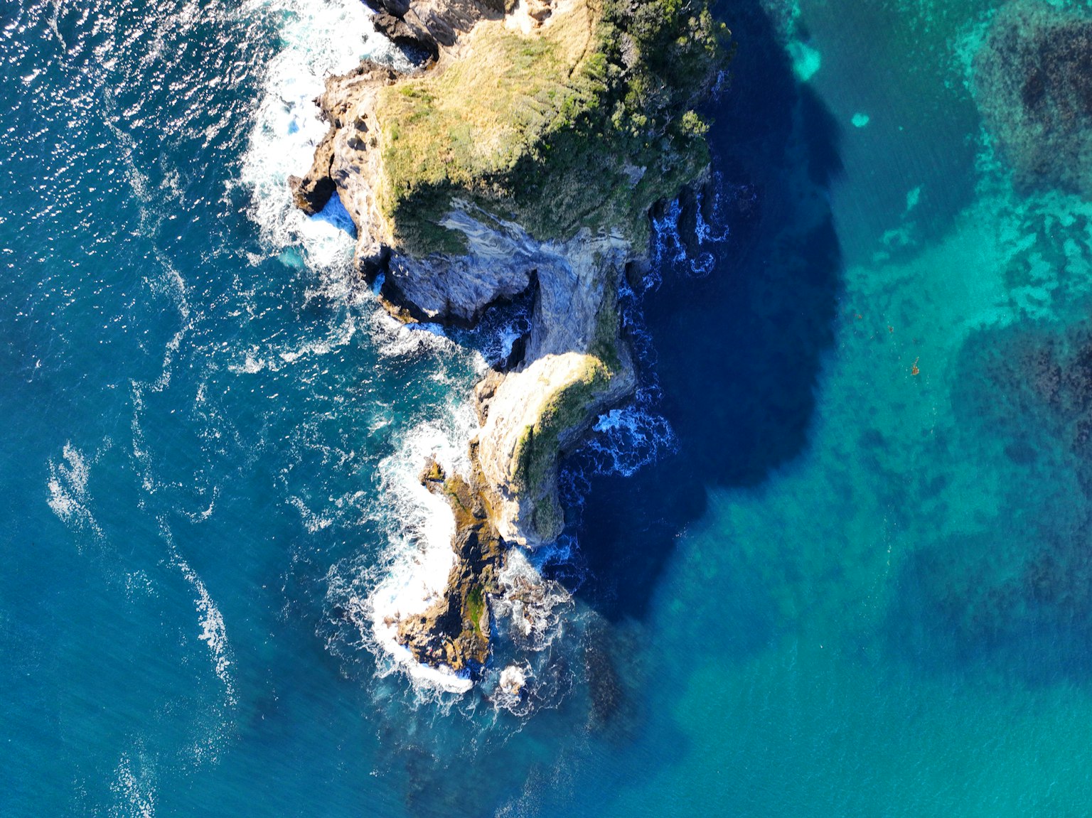 Vista aérea de una pequeña isla rodeada por un océano azul