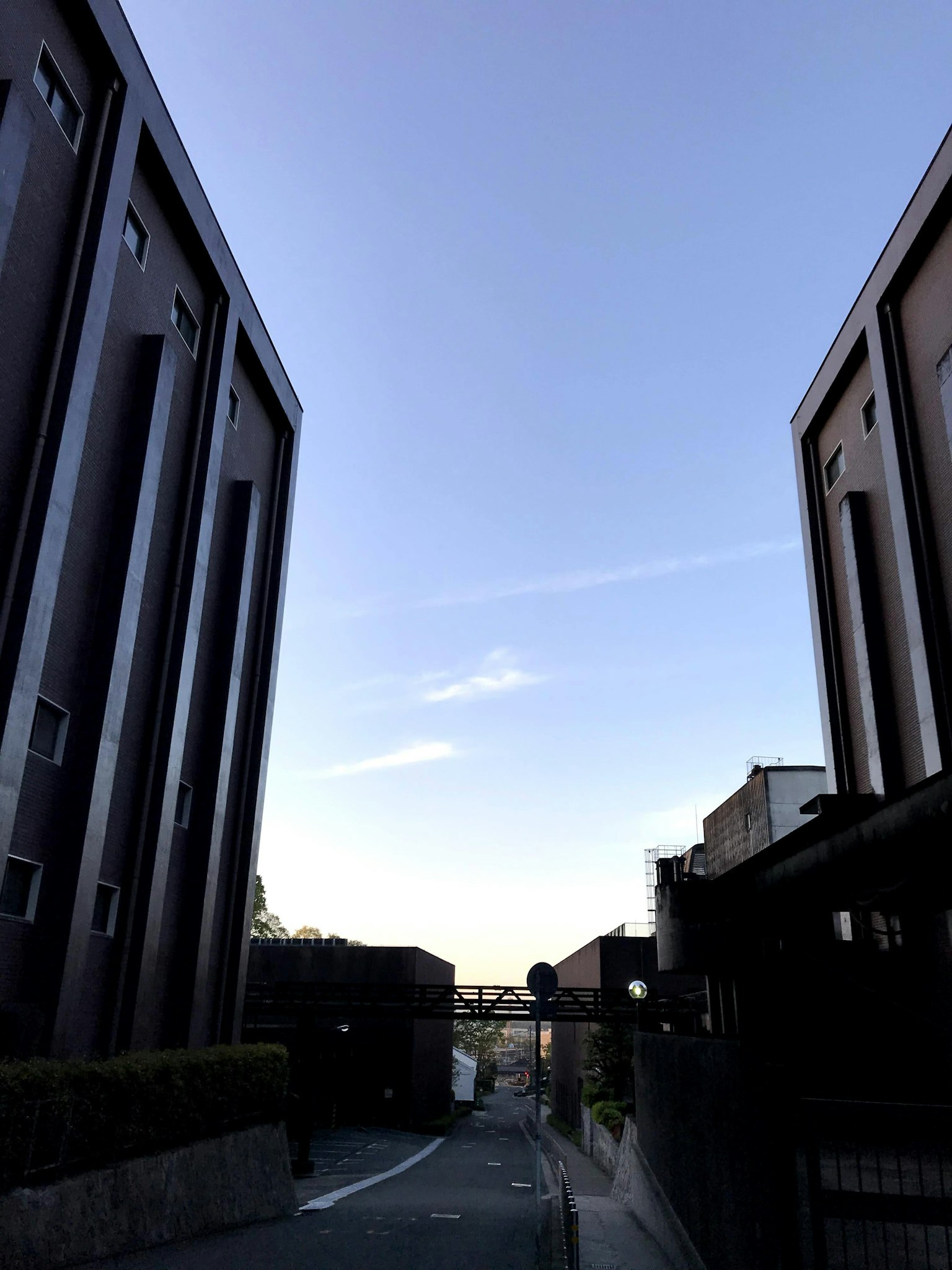 Strada stretta che porta verso un cielo blu fiancheggiato da alti edifici