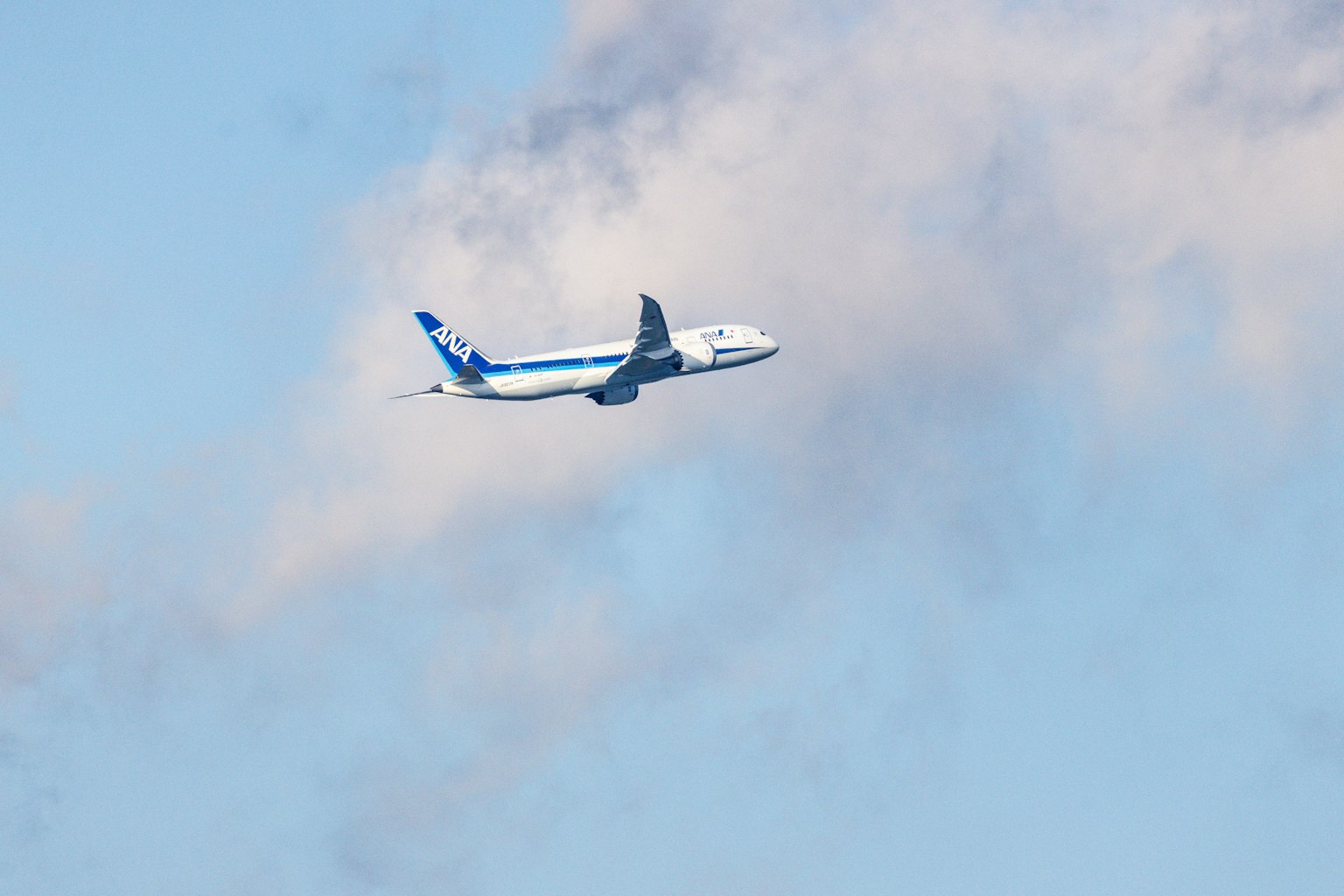青空を飛ぶ飛行機の画像　白い雲が背景にある