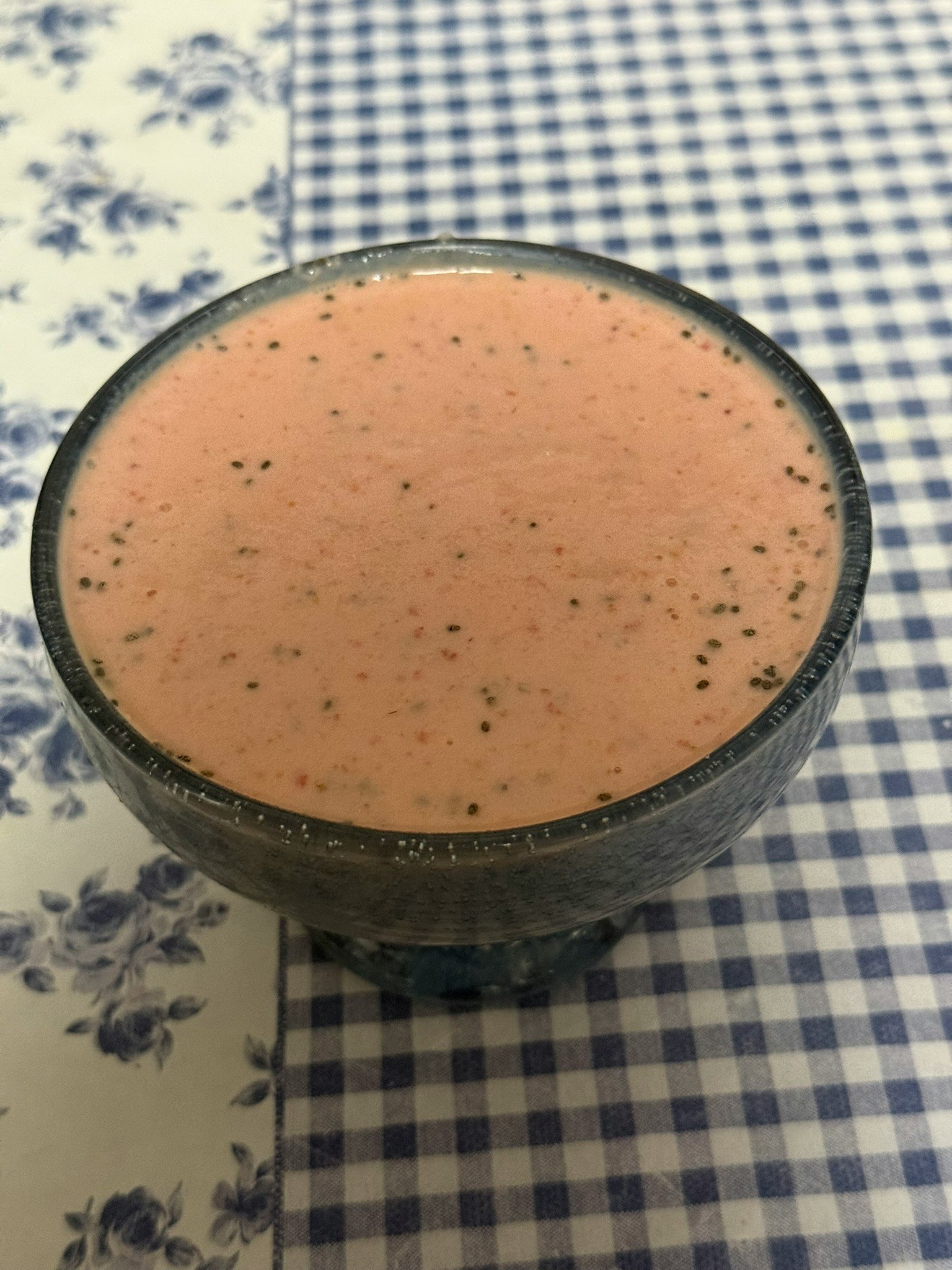 クリーム色のスムージーがガラスの器に入っている青と白のチェック柄のテーブルクロスの上に置かれている