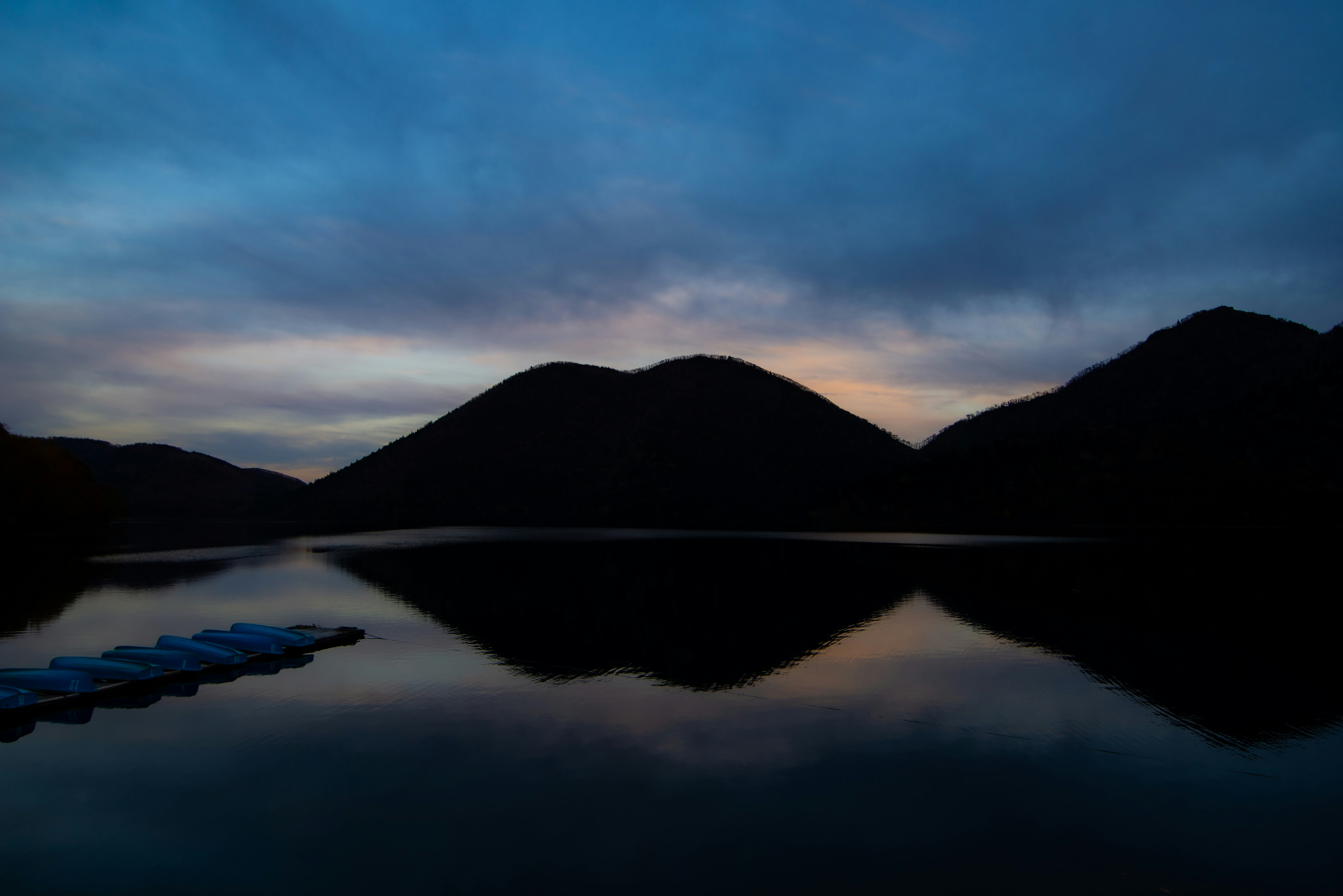 mountain silhouettes reflected on a calm lake at dusk