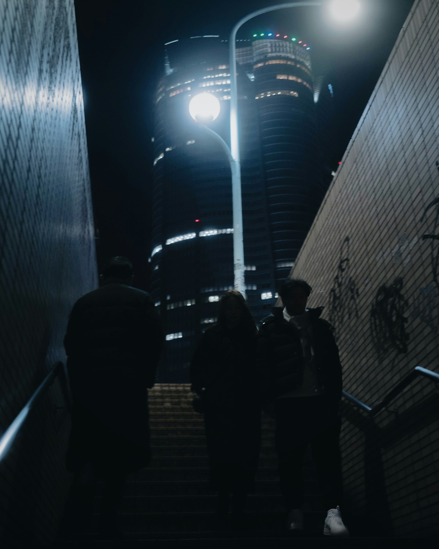 夜晚人们走下楼梯，背景是城市灯光