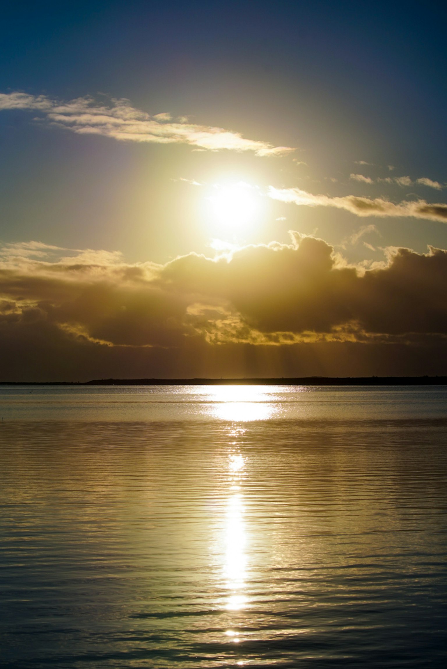 Serene ocean view with sun shining through clouds