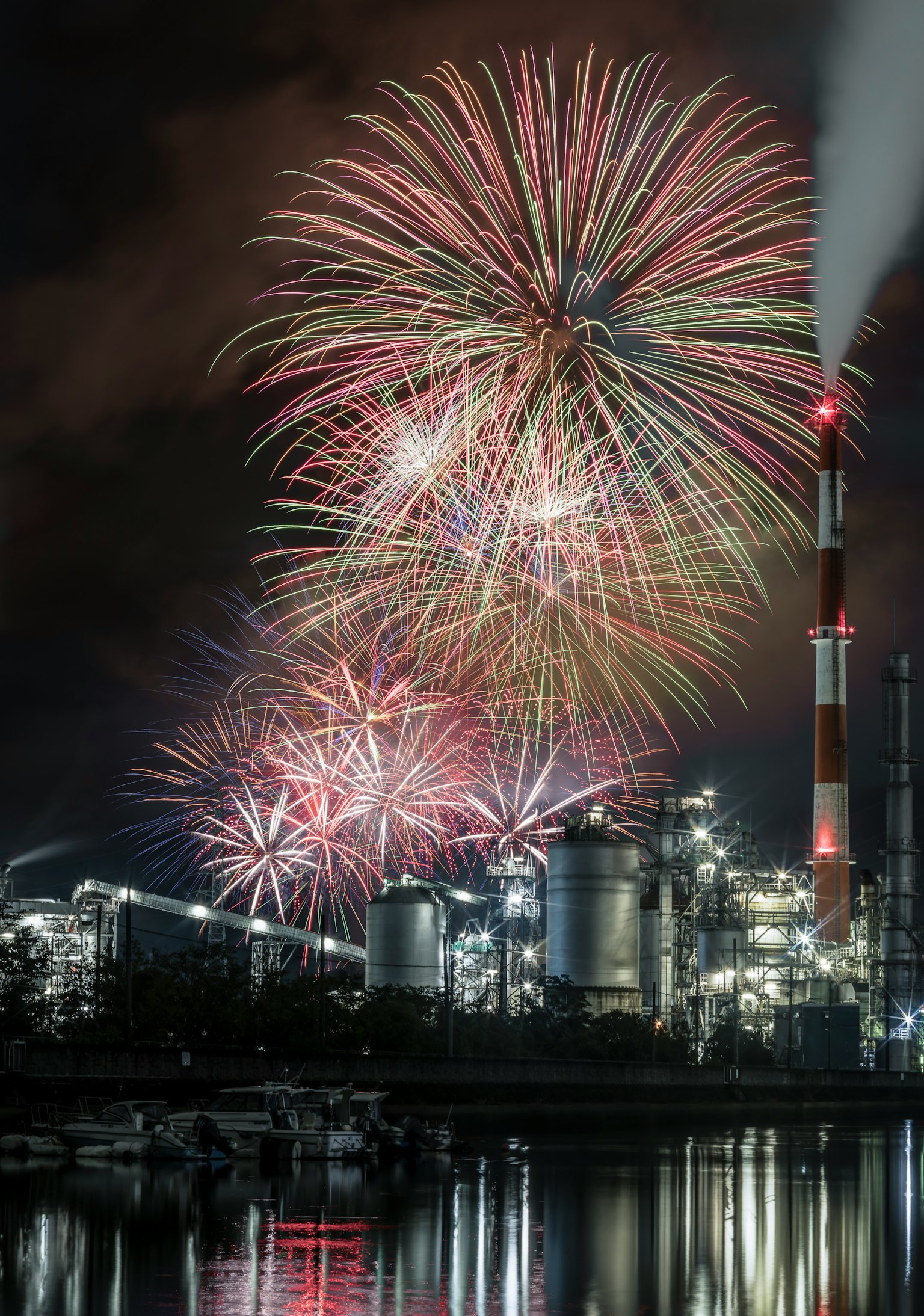工場の背景に花火が打ち上げられる夜景
