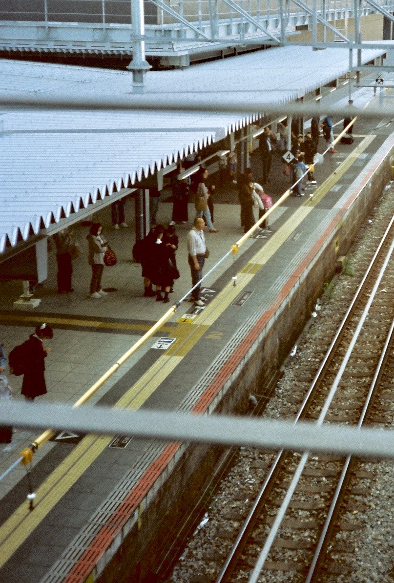 ホームを歩く人々と線路が見える駅の風景