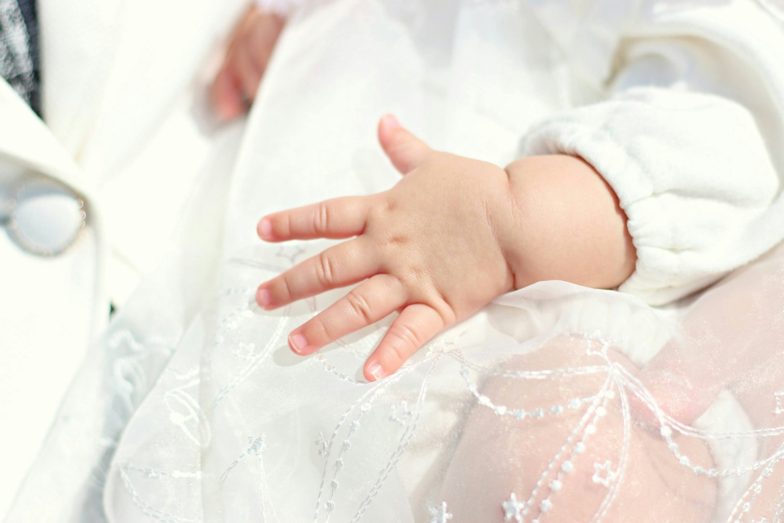 La mano de un bebé descansando sobre un vestido blanco