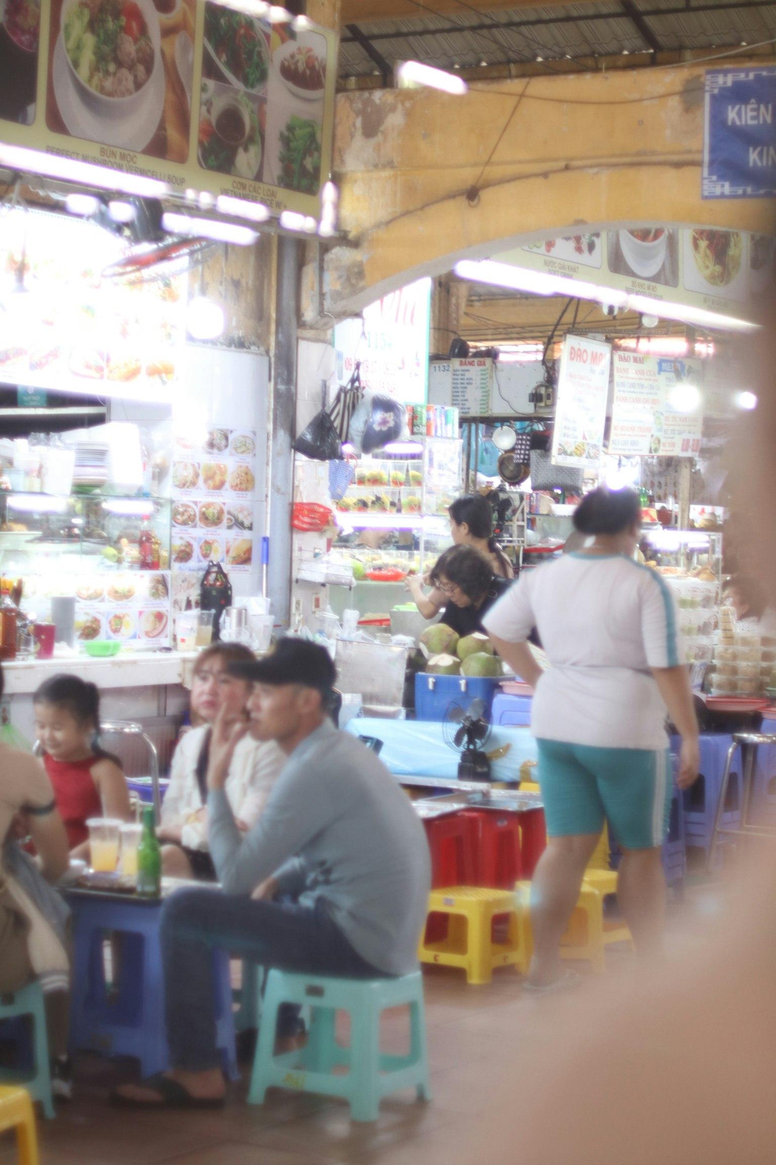 屋台の食堂で食事を楽しむ人々とカラフルな椅子が並ぶ風景