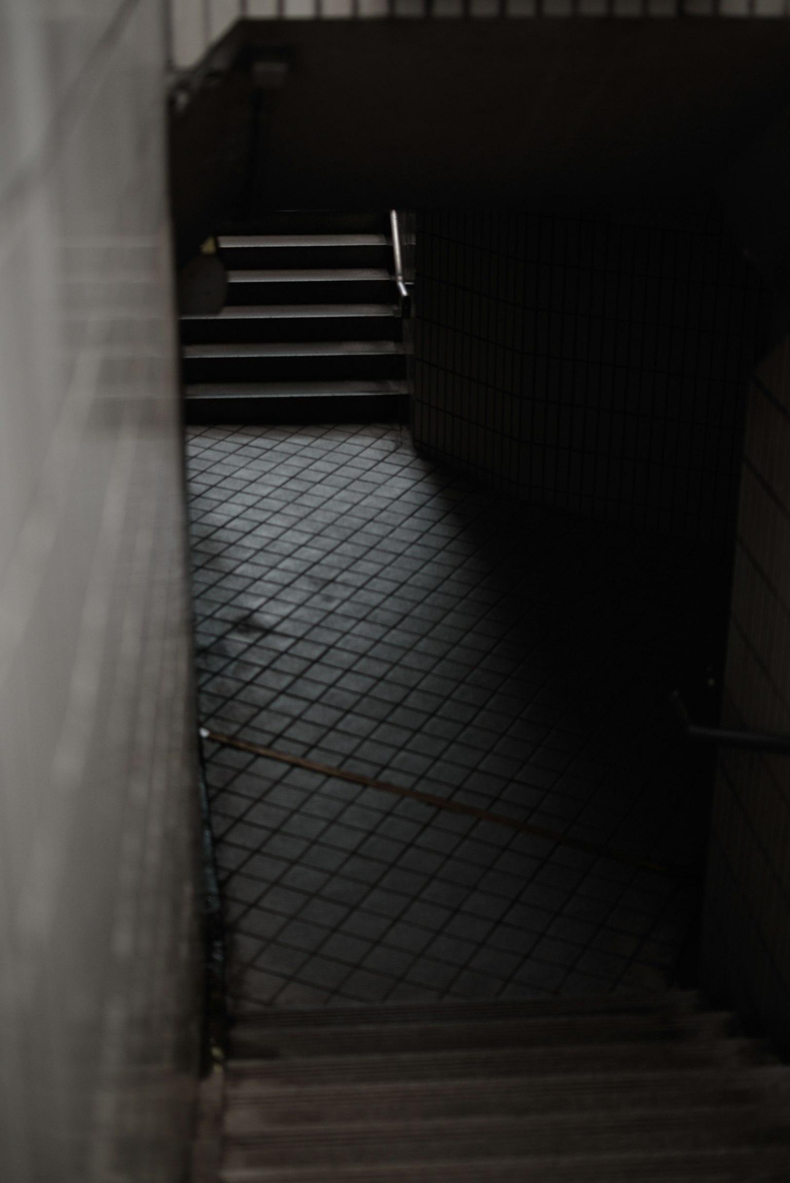 A dimly lit staircase with a handrail and tiled floor