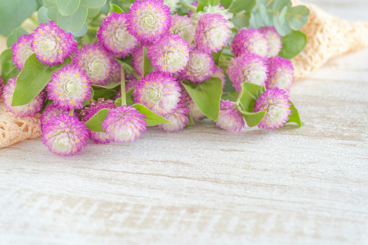 Un mazzo di fiori viola con foglie verdi posato su un tavolo di legno
