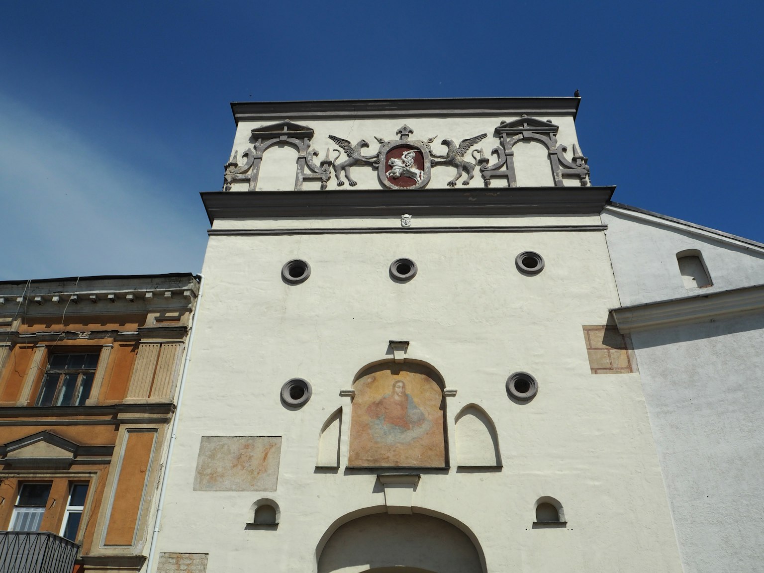 Ein Gebäude mit weißen Wänden, dekorativen Bögen und einem Wappen
