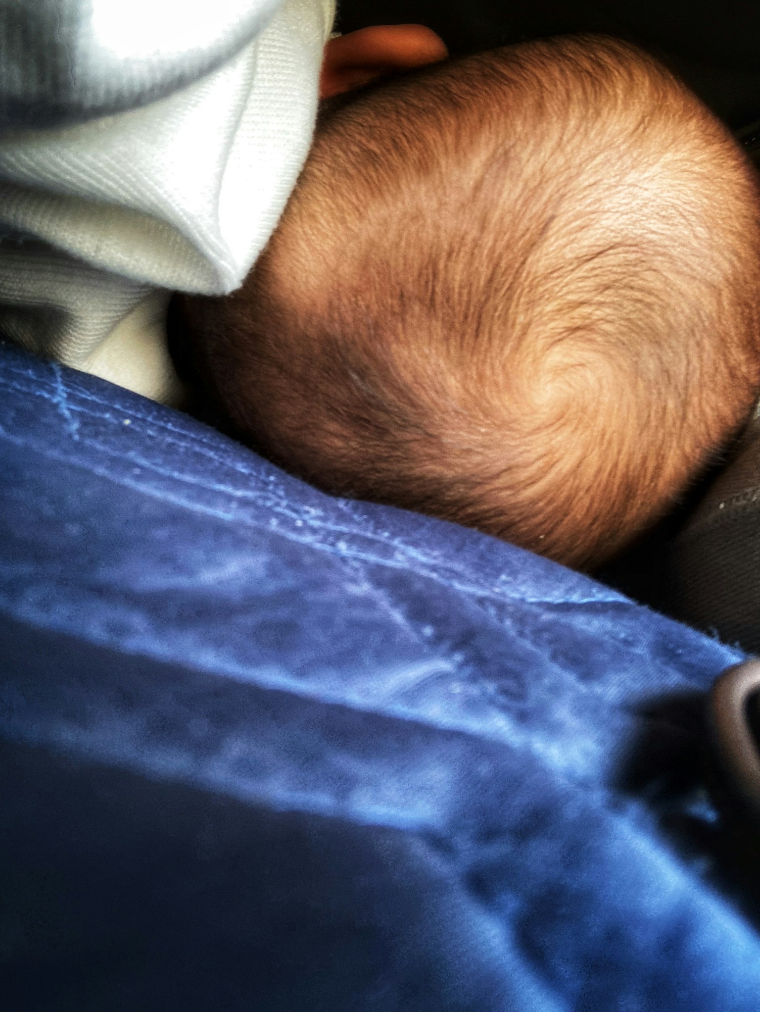 Bild zeigt den Hinterkopf eines Babys, das auf einer weichen blauen Decke ruht