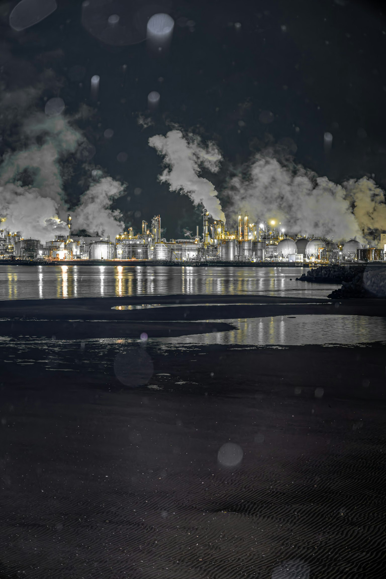 Nachtansicht eines Industriegebiets mit Rauch und Spiegelungen