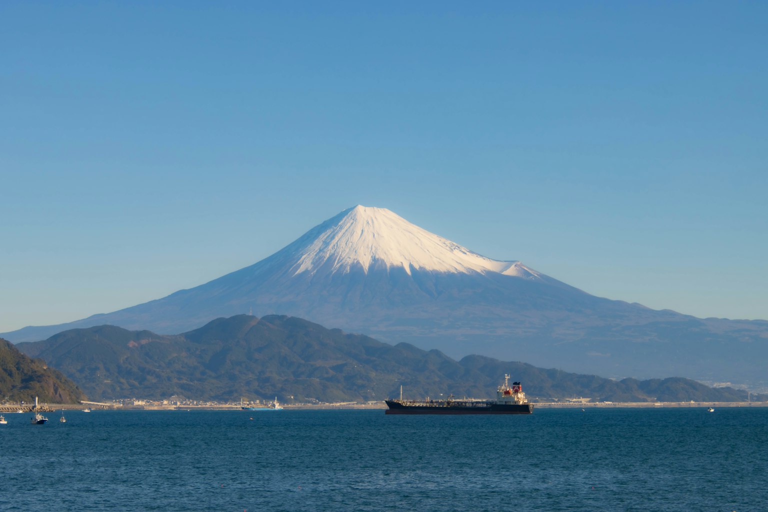 Vista panoramica del Monte Fuji coperto di neve con una nave che naviga nel mare